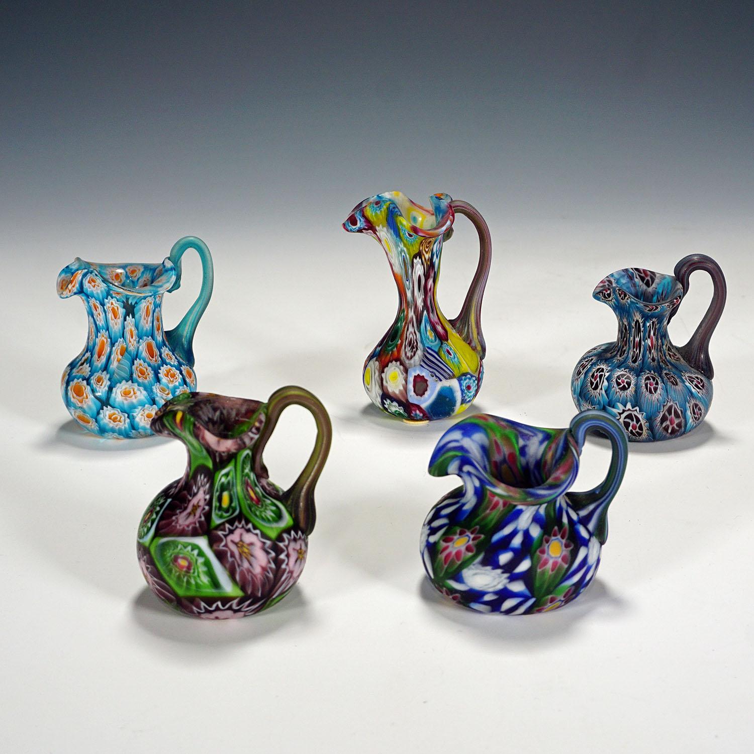 A set of five small murrine glass jugs, manufactured by Vetreria Fratelli Toso around 1910. The jugs are executed with polychrome multicoloured millefiori murrines and have an acid etched matte finish. They are authentic examples of early 20th