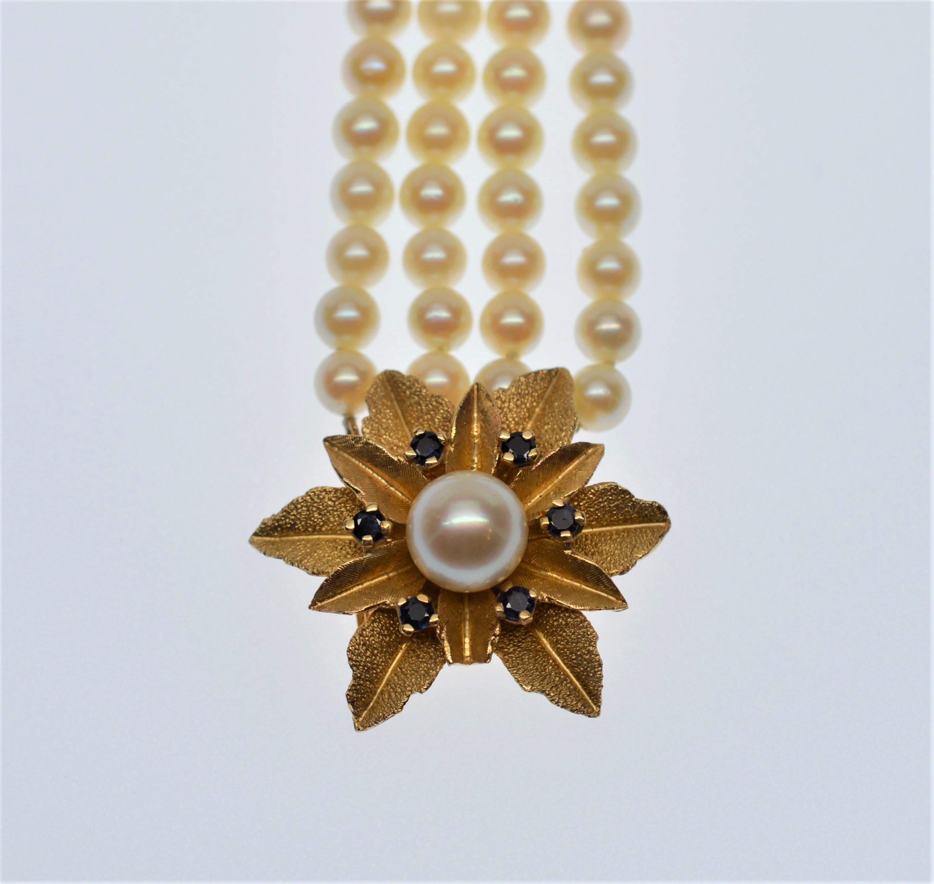 1950's Style Five Strand Pearl Bracelet with feature 14 Karat Gold & Sapphire Floral Burst Clasp. Made of over one hundred 5 1/2 mm fine genuine AAA Akoya Pearls, this finely constructed 7 inch bracelet blooms with personality featuring a large