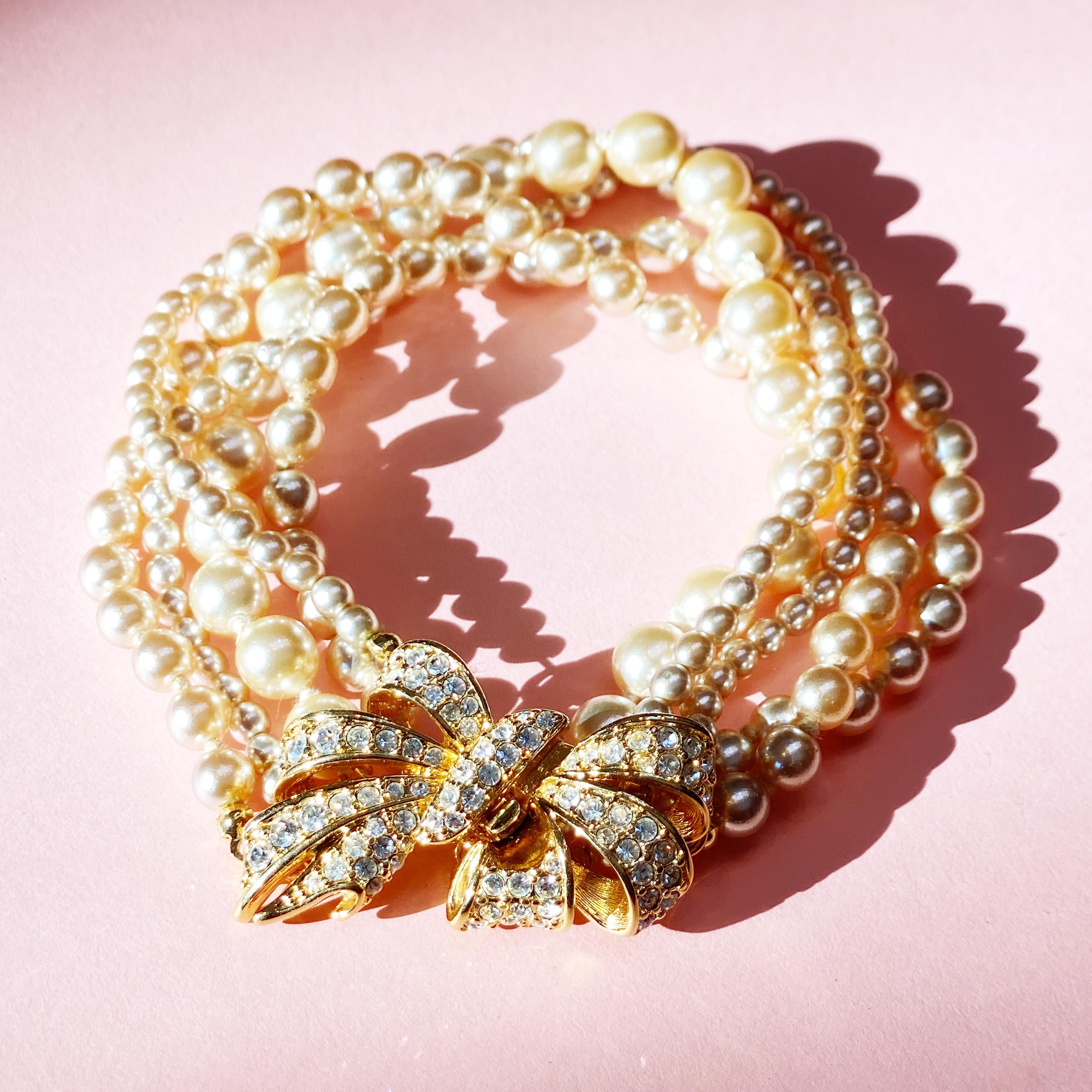 - Vintage item

- Consists of five faux pearl strands

- Gold plated

- Crystal rhinestone accents

- Hidden box clasp

- By Nolan Miller (signed on clasp)

- Circa 1980s

- Estate acquired

- Excellent vintage condition