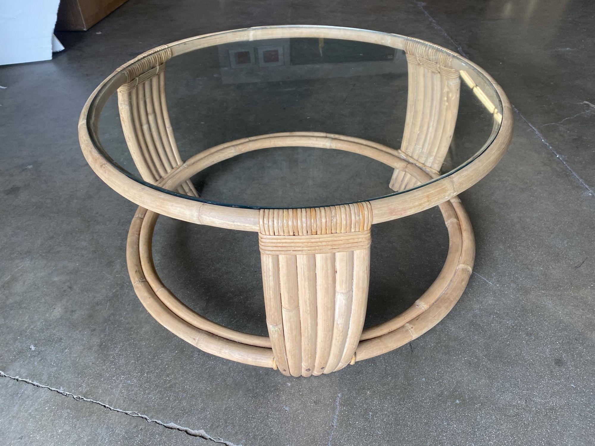 Five strand rattan coffee table, circa 1940. The unusual round base's circular form is echoed throughout the piece with an added triangular form and a small interior circle. The table also features a round glass top.

Professionally restored to