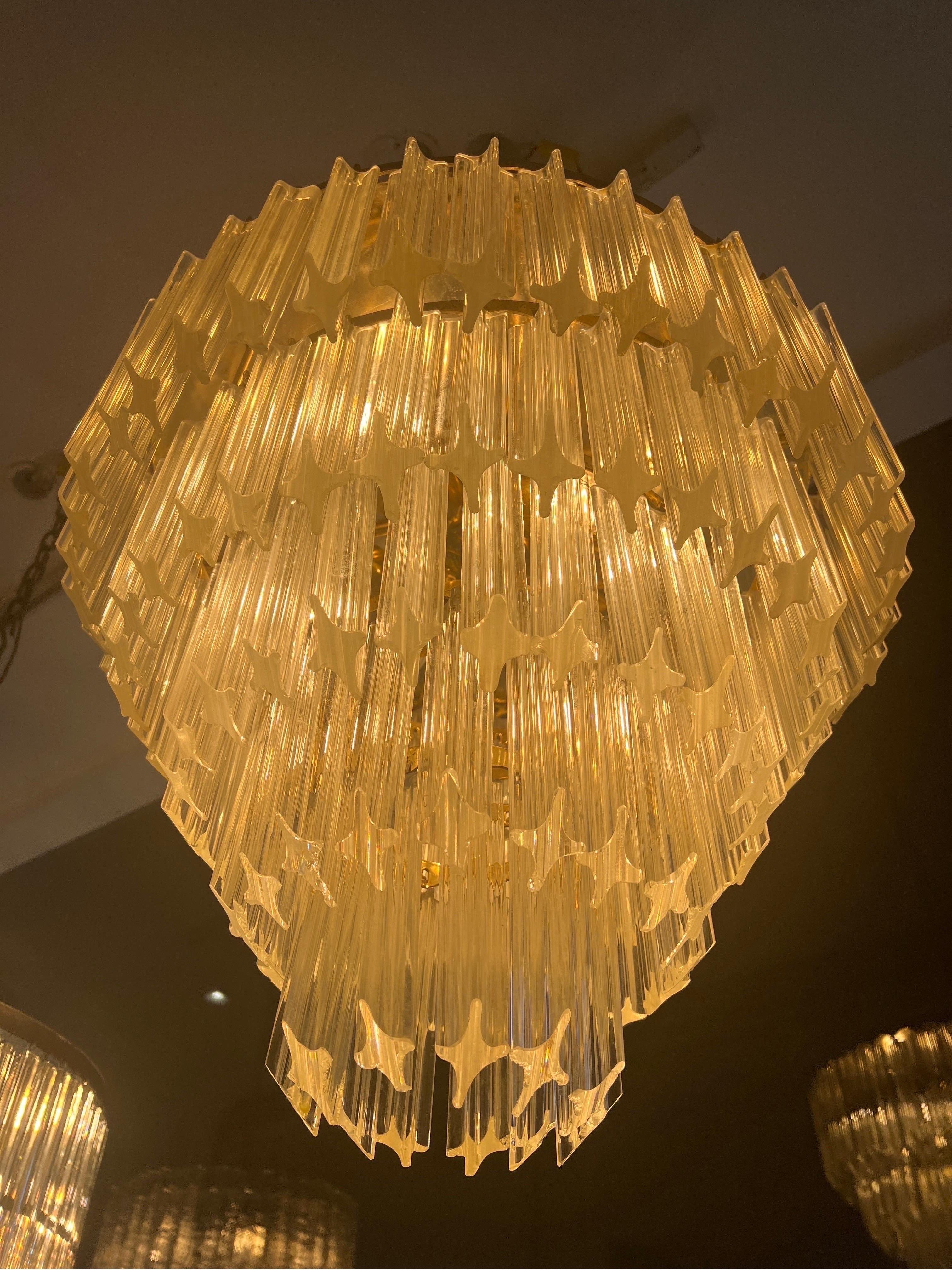 A Fabulous five tiered cascading Murano glass  chandelier consisting of 200 individually cut glass pieces & supported by a brass structure with a mirrored brass plate to the top . There’re six directional bulbs to the inside allowing for the lights
