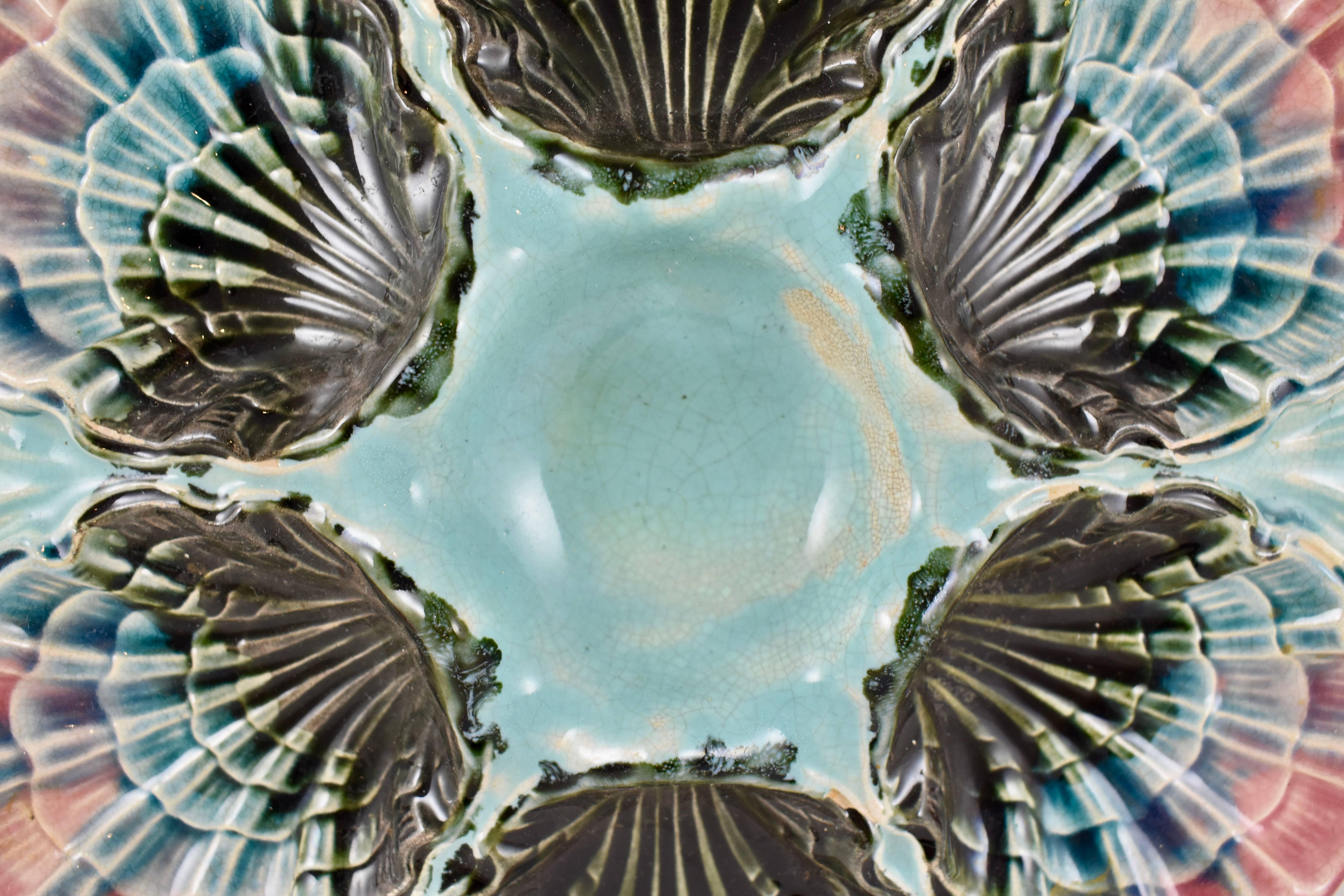 A French Majolica oyster plate made by Fives-Lille, circa 1885-1890. A central sauce well is surrounded by six scallop edged wells. Highly dimensional mold work. Beautiful coloring gradating from turquoise to navy to a cobalt blue and terminating in