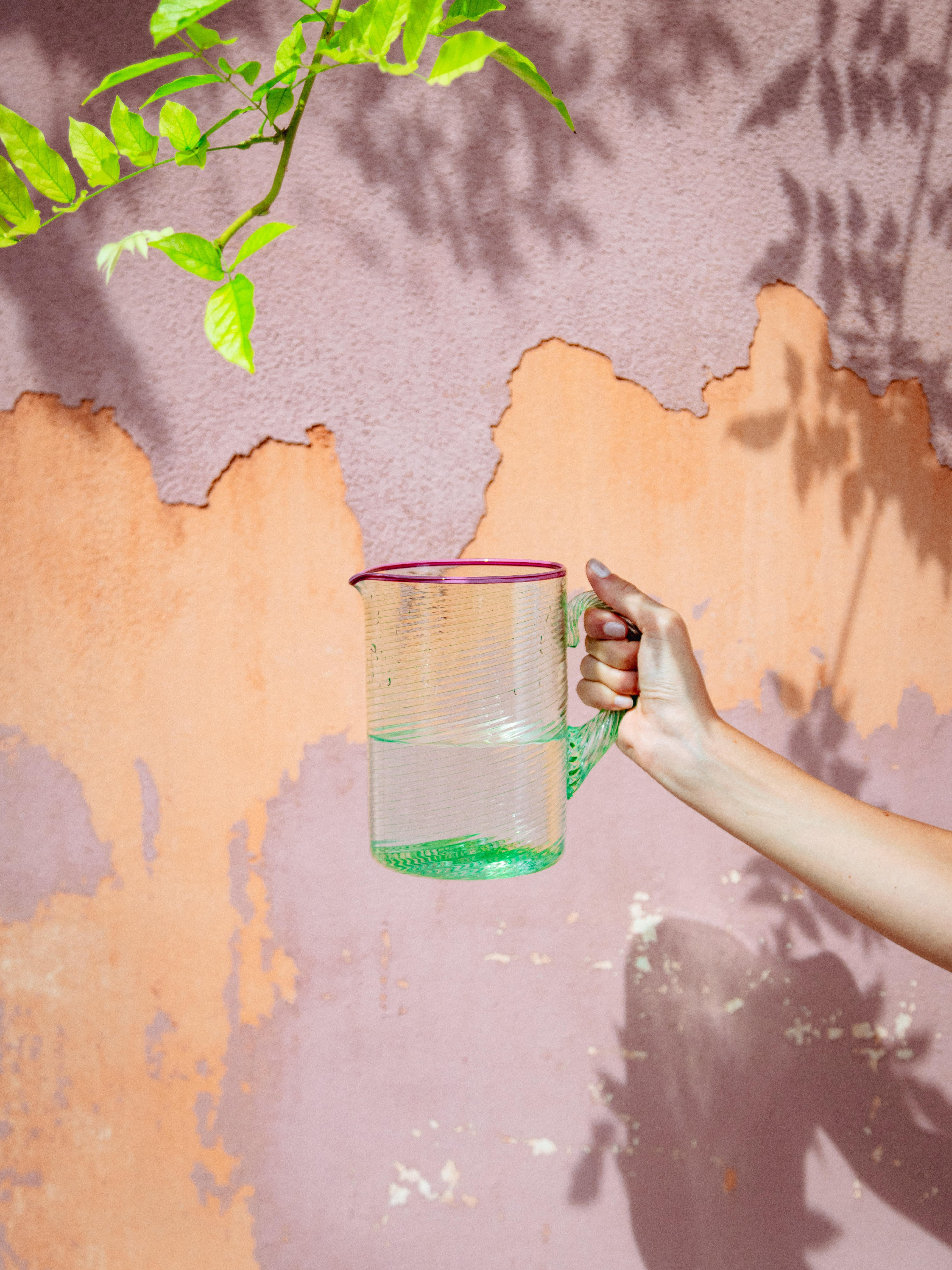 Der Fizzy Jug ist aus kostbarem grünem Murano-Glas mundgeblasen und mit einem heißgesiegelten rosa Rand versehen. Giberto erinnert sich: 