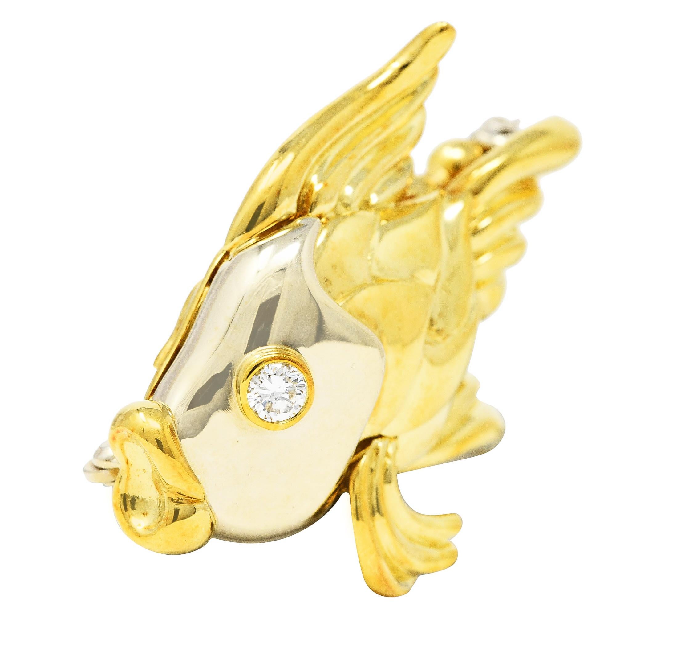 Designed as a stylized goldfish with a white gold face, puffed scales and flowing fins. Accented by a round brilliant cut diamond eye weighing approximately 0.14 carat total. Eye clean and bright - bezel set. Completed by hinged pin stem with