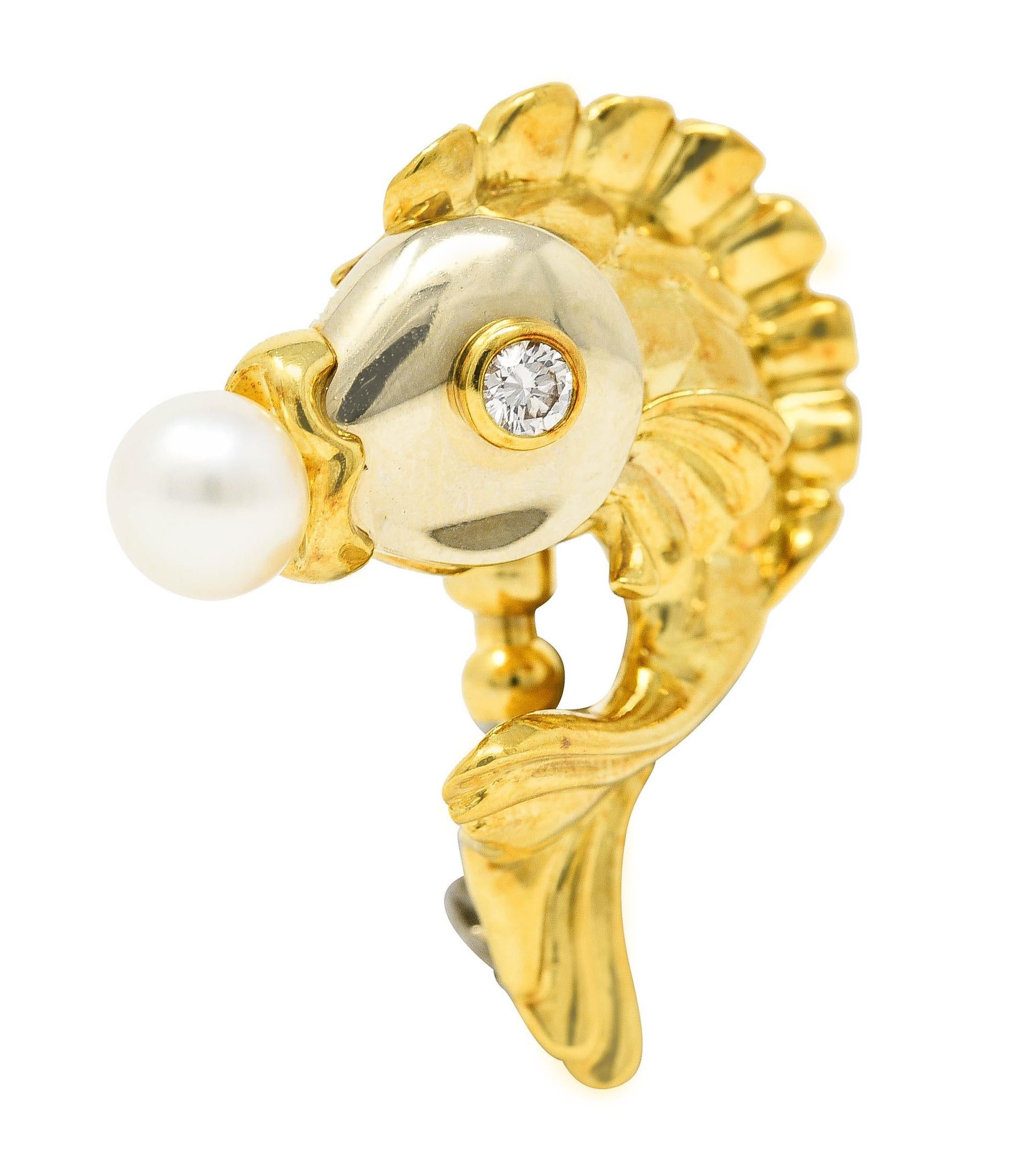 Designed as a stylized koi fish with a white gold face, puffed scales and fluted fins. Accented by a round brilliant cut diamond eye weighing approximately 0.14 carat total. Eye clean and bright - set in a yellow gold bezel. Accented by a 7.5 mm