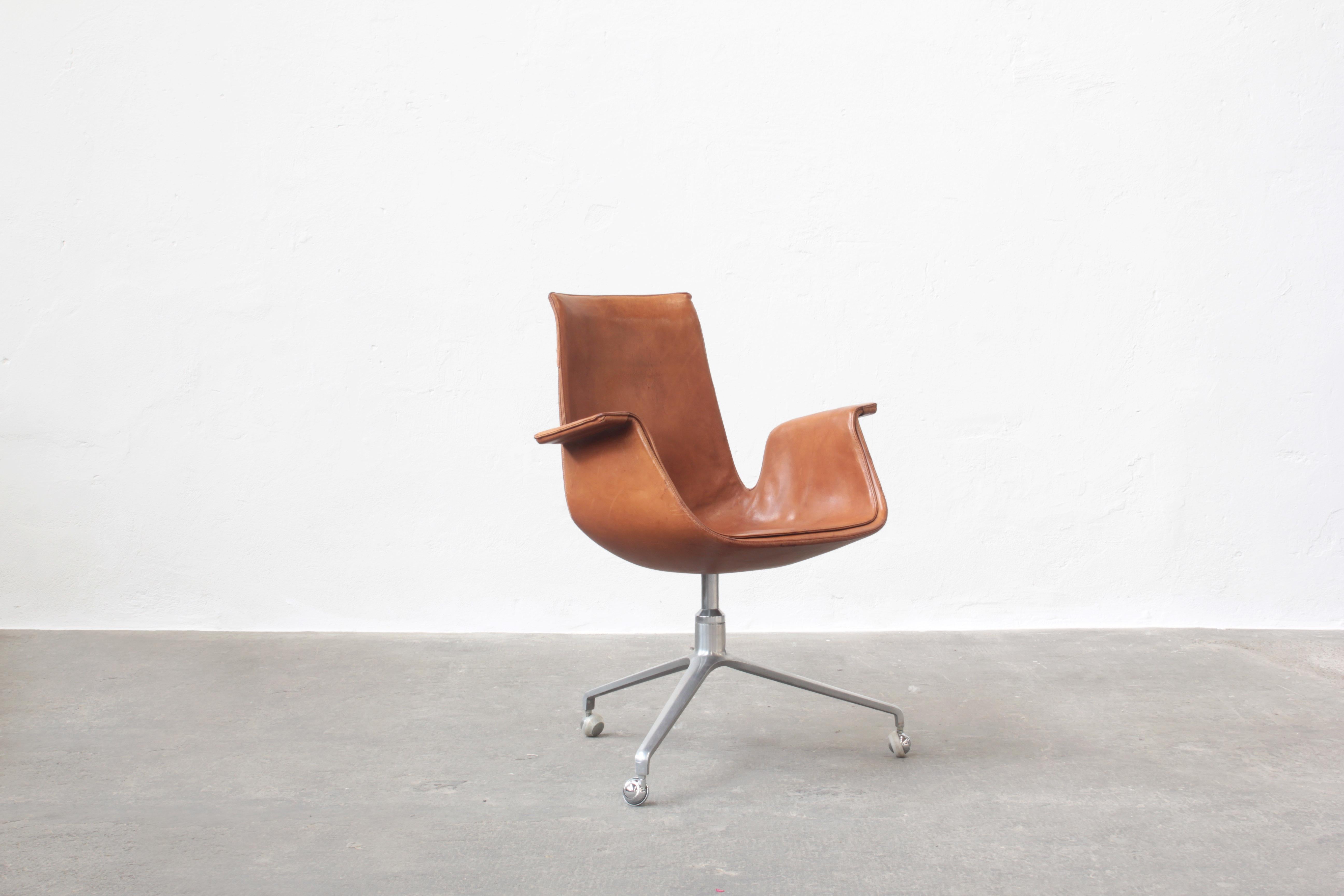 Beautiful tulip chair designed by Preben Fabricius and Jørgen Kastholm and produced by Alfred Kill International. 
The chair comes in an original condition with beautifully patinated leather in cognac brown.
The leather has some small scratches on
