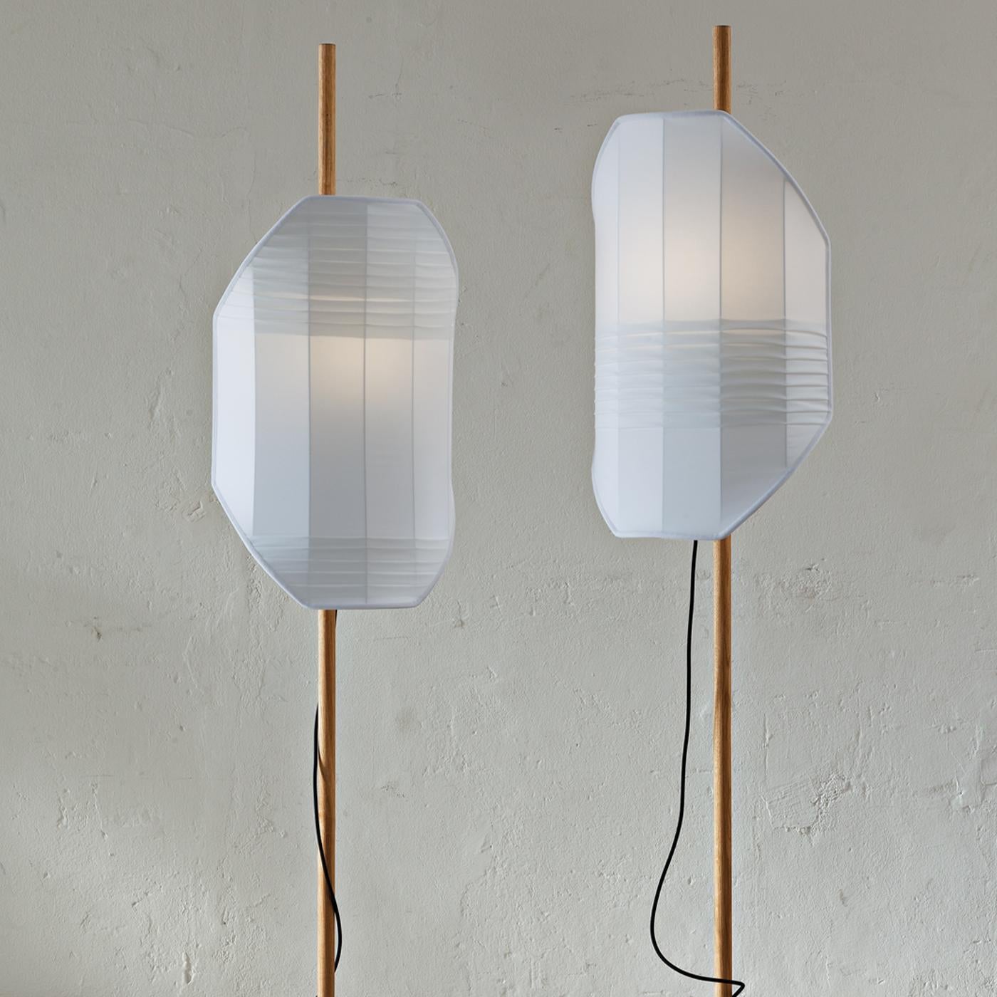 This lamp takes inspiration from the image of a flag hammered into a stone, as the gesture of marking a place off the beaten track with a visible sign. A luminescent screen hung from an oak pole, tucked into a piece of circular 