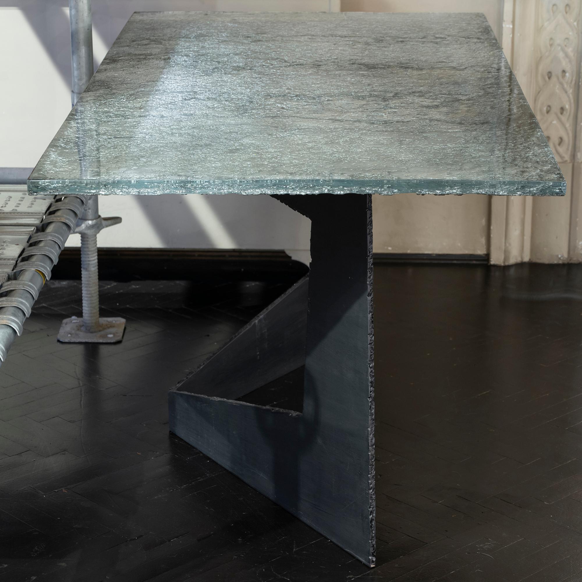 Writing desk part of the Flair Edition collection, steel base with black finish, 24 mm. thick cast glass top with raw edges and silver finish.
