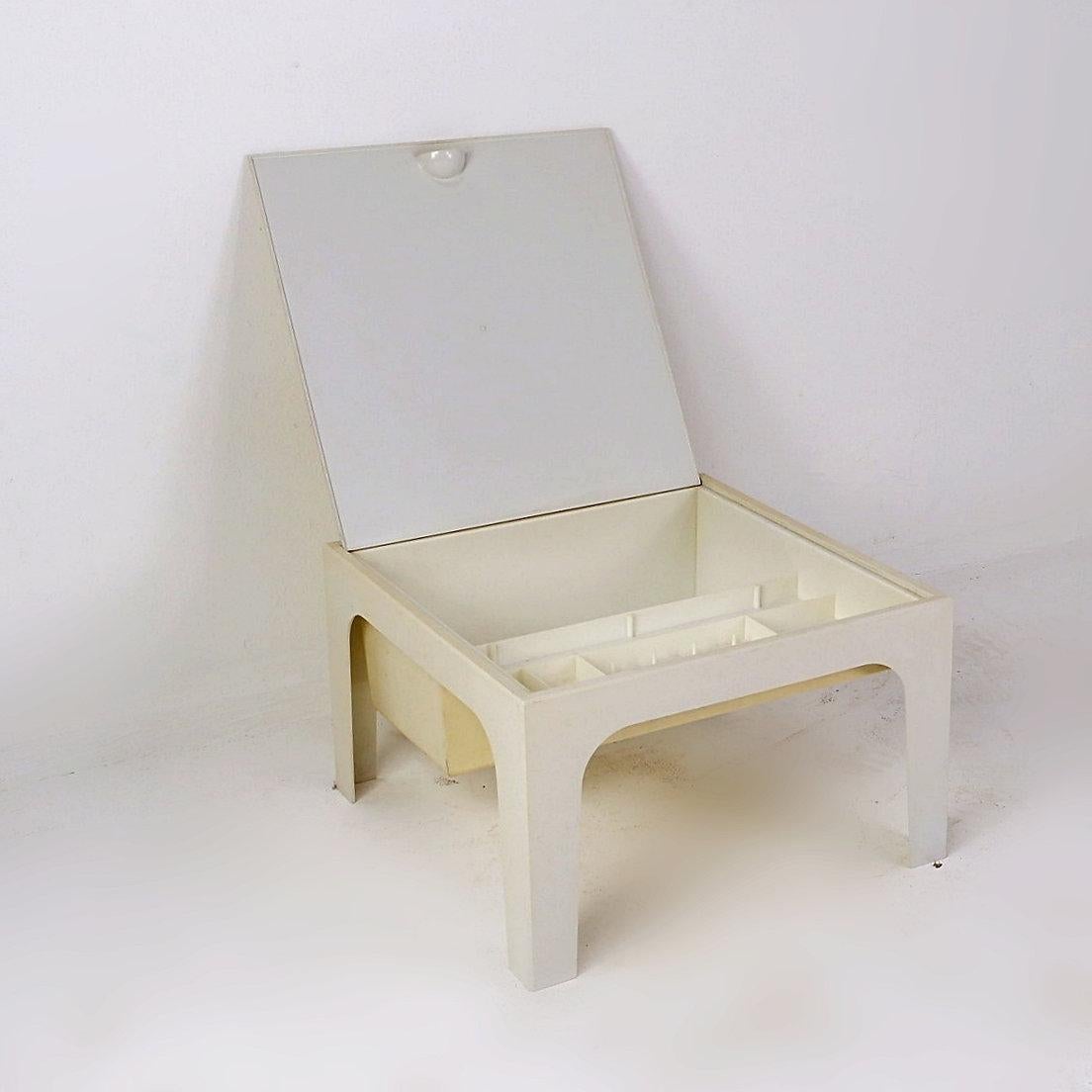 Die Platte dieses weißen Kunststoff-Couchtisches verbirgt eine Ablagefläche für Nähzubehör. Aber dieses kleine Möbelstück ist nicht auf diese Verwendung beschränkt. Mit seinen kleinen Fächern kann er Schmuck im Schlafzimmer und Zeitschriften oder