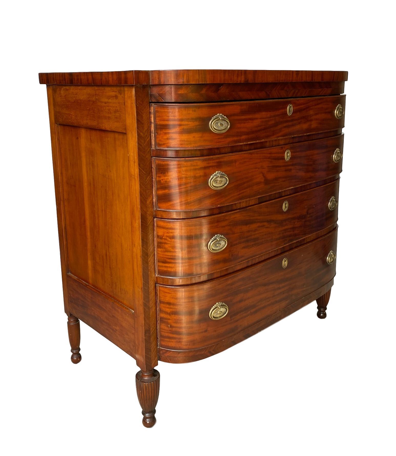 Flame mahogany bow-front chest-of-drawers/dresser, Scottish, circa 1860, with four long drawers with distinctive bowed ends and original brasses, with chevron inlay to the outer carcase, with shaped top, on turned and reeded legs.
In excellent