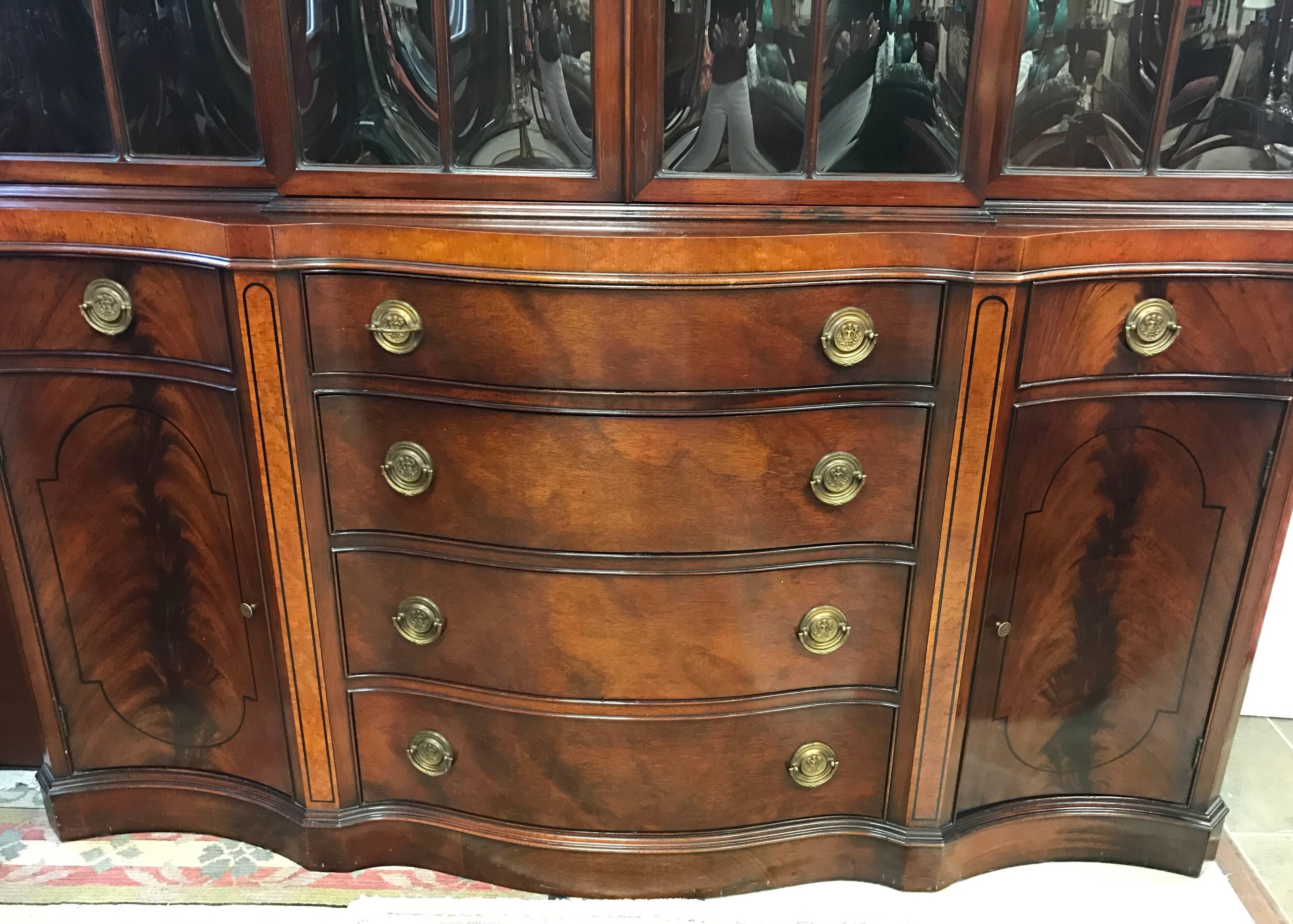 Magnificent flame mahogany two part breakfront or bookcase. Top part has four glazed doors that open to three shelves with grooves to display china. Bottom part has drop down butler's desk having a tooled leather writing surface with smaller drawers
