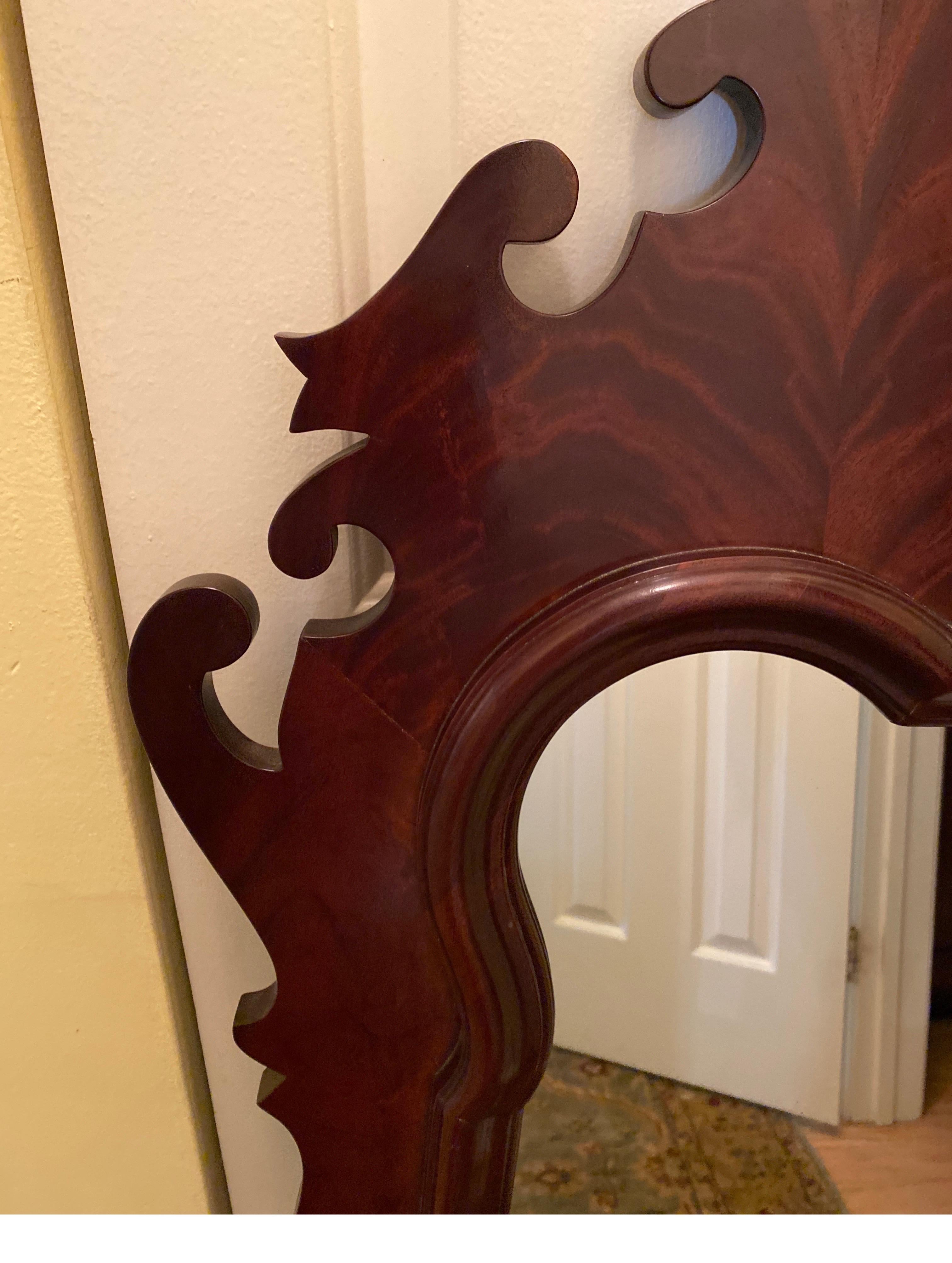 Elegant flame mahogany beveled mirror with Chippendale frame. The shapely molding around the beveled glass. The Swirly figured book-matched crotch mahogany veneer face. Top and bottom carry a complicated detail of scrollwork often used by