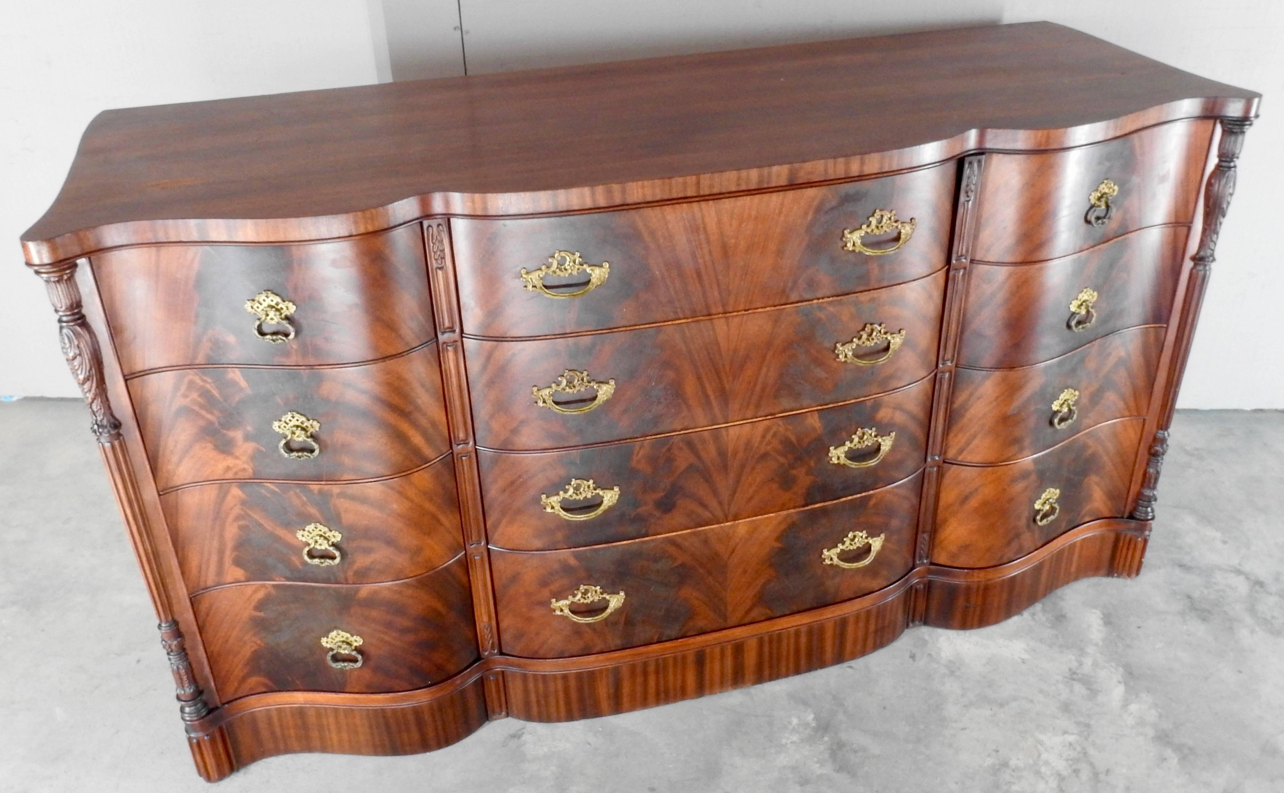 We are offering a superb flame mahogany dresser. An abundance of dove-tailed drawers are decorated with functional bronze pulls. The front is elegantly curved and is accented with carved spindles on each end.