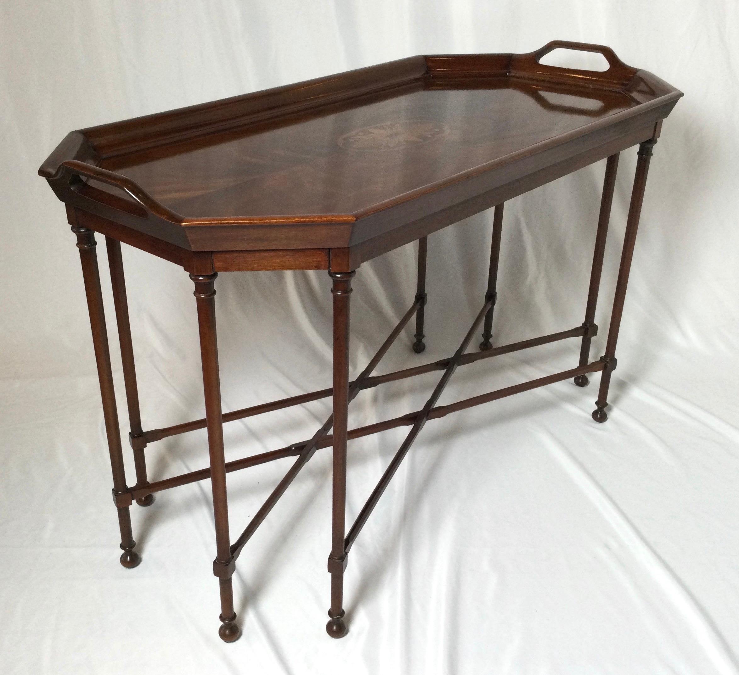 Elegant formal flame mahogany cocktail table with inlaid center medallion. The handled top with attached slender legs with a criss-cross stretcher base. This table is a smaller size with a European height.