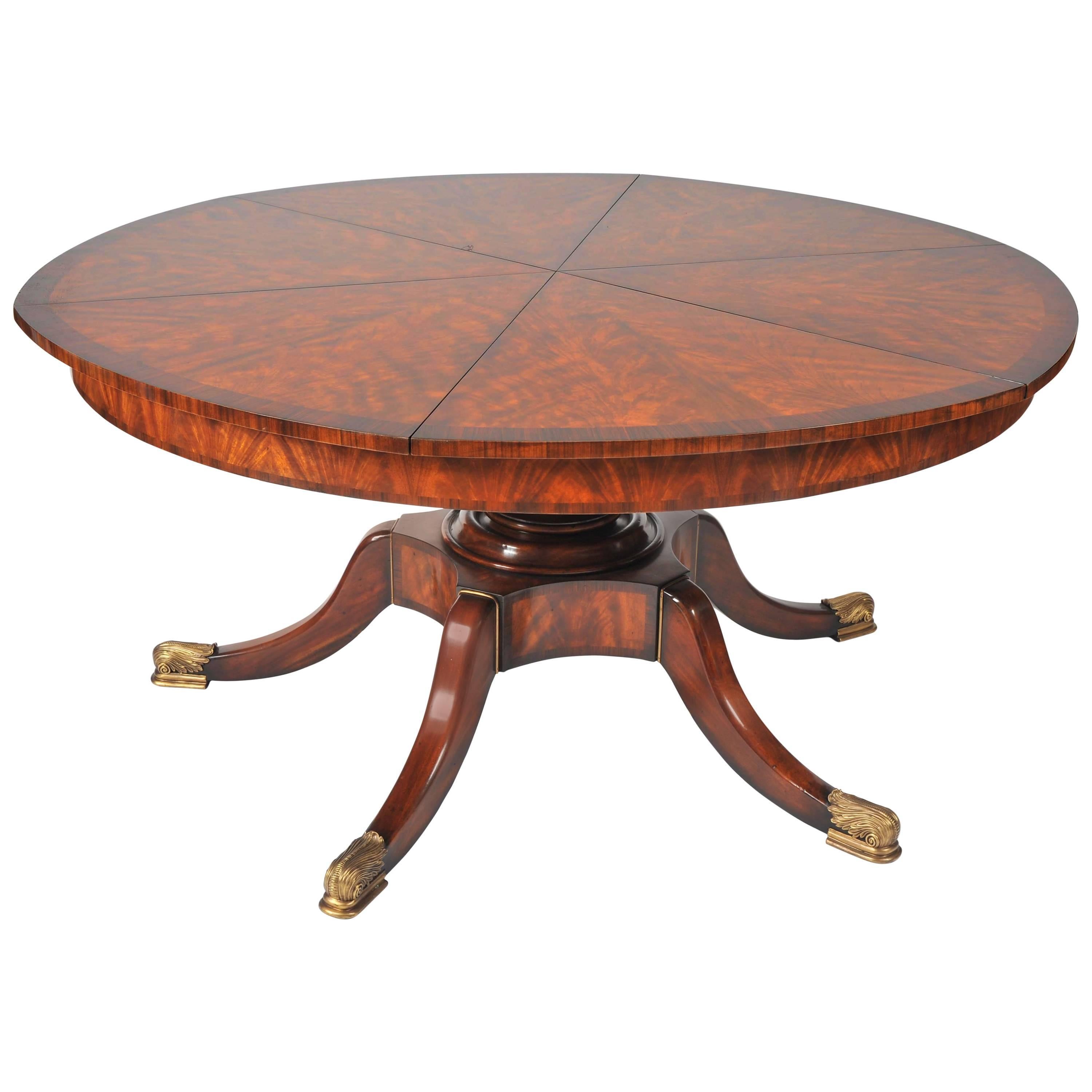 This stunning and beautifully designed flame mahogany segmented circular extending table is in the Regency style, and features leaves that are internally stored. When the table sections are pulled out, it reveals the leaves set inside, and can then