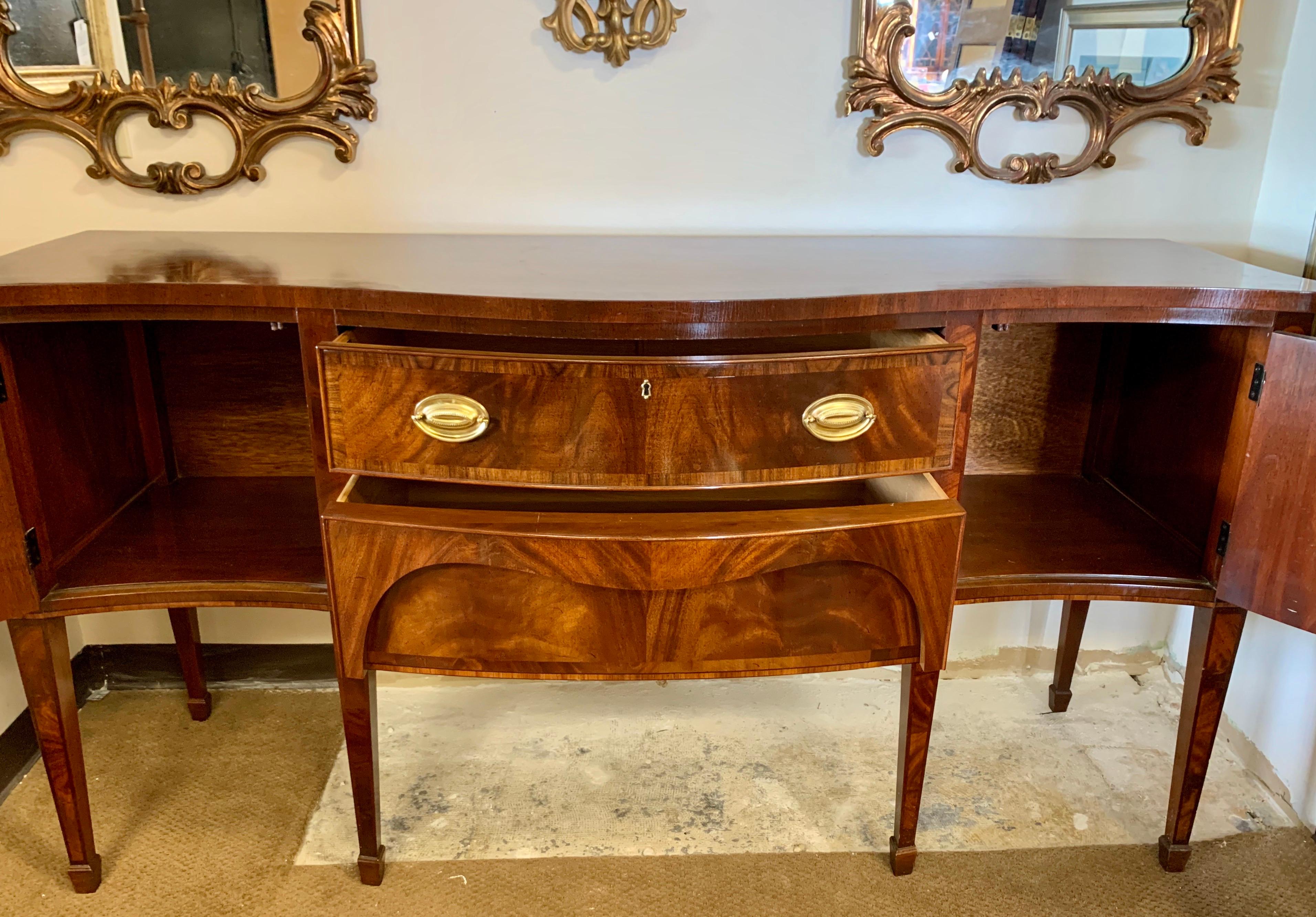 Stunning flame mahogany buffet with all original brass hardware and intricate inlay. Multiple drawers/compartments for all of your flatware and accessories. Handmade by Fancher in New
York, USA, circa 1970s.