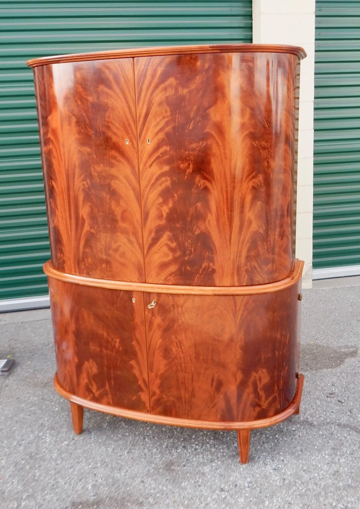 Storage cabinet or sideboard rendered in highly figured bookmatched flame mahogany. Designed for and sold at Nordiskakompaniet department store in Stockholm, Sweden in the late 1940s. With four doors to provide lots of storage capacity. With all