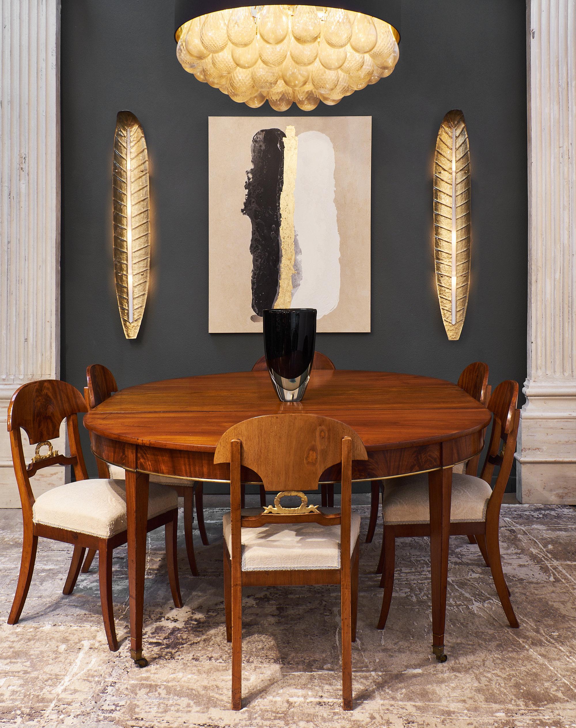 A superb Directoire flamed mahogany dining room table with two leaves. We love the brass trim and tapered legs on casters. Each leaf adds an additional 23.75” to the length of the table. The wood is a beautiful warm color, with fantastic antique