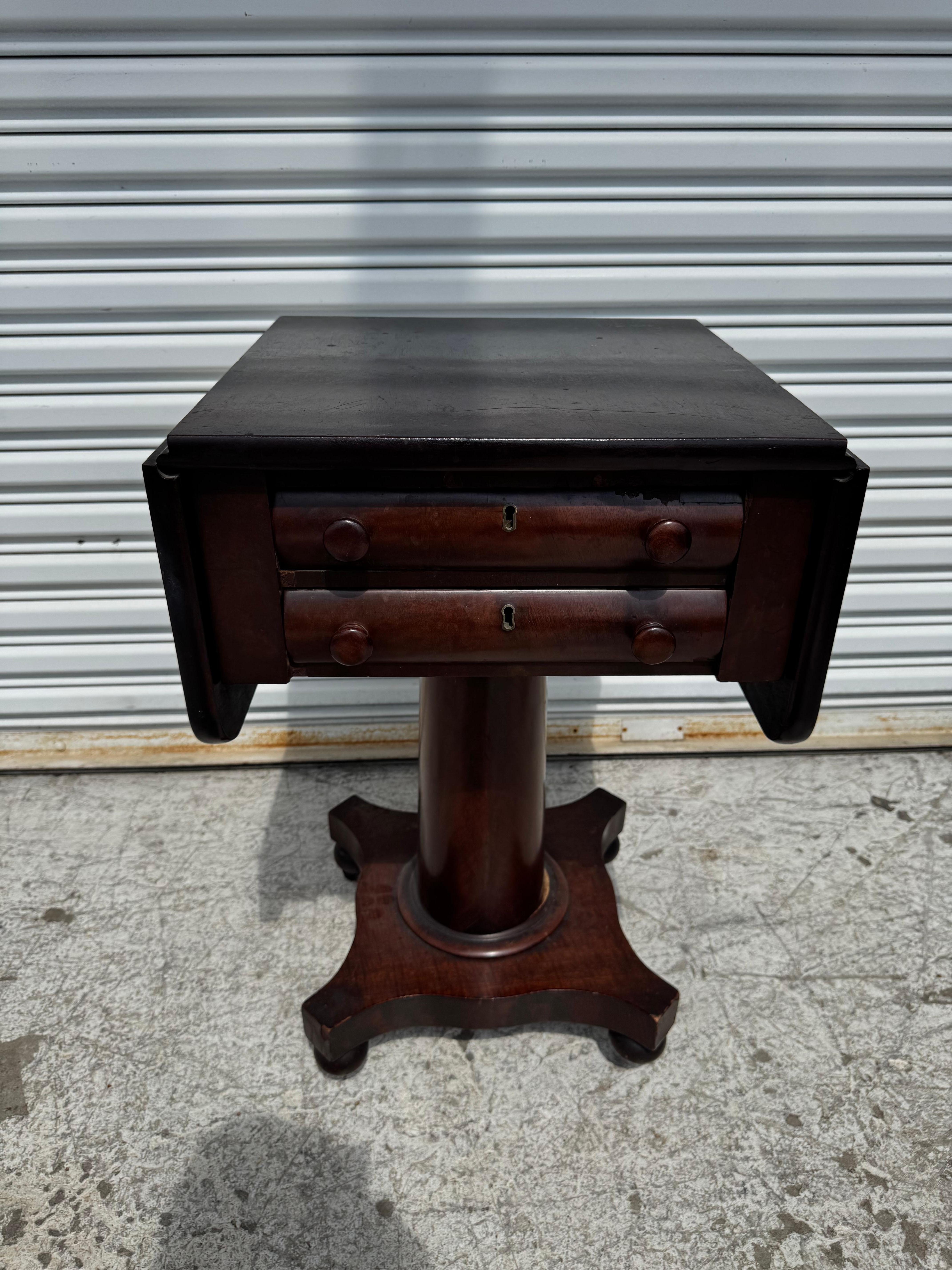 This is what they called a sewing or work table.
The table is made of flaming mahogany.
I has two drawers for storage and stands on a pedestal base.
The table has a pair of drop leaves that doubles the size of the top.
It sits on ball feet that rest
