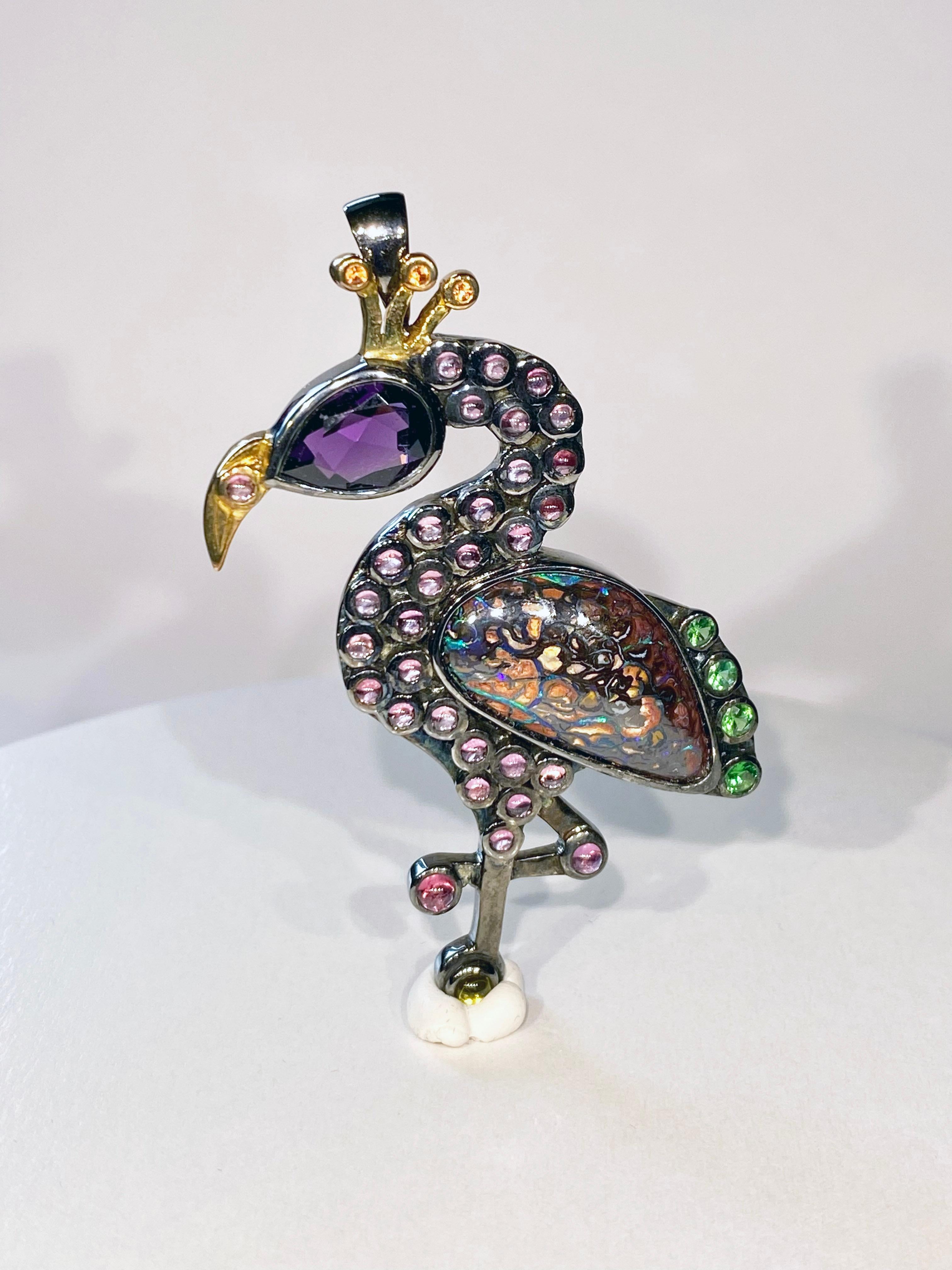 A Flamingo Pendant/Brooch in Blackened Silver with 18kt Gold Plating, set with Australian Boulder Opal Body, A Pear Cut Amethyst Head, Round Yellow Sapphire Crest Ornaments, Pink Tourmaline Cabochons & Tsavorite Garnet Rounds.
This Jewel can be worn