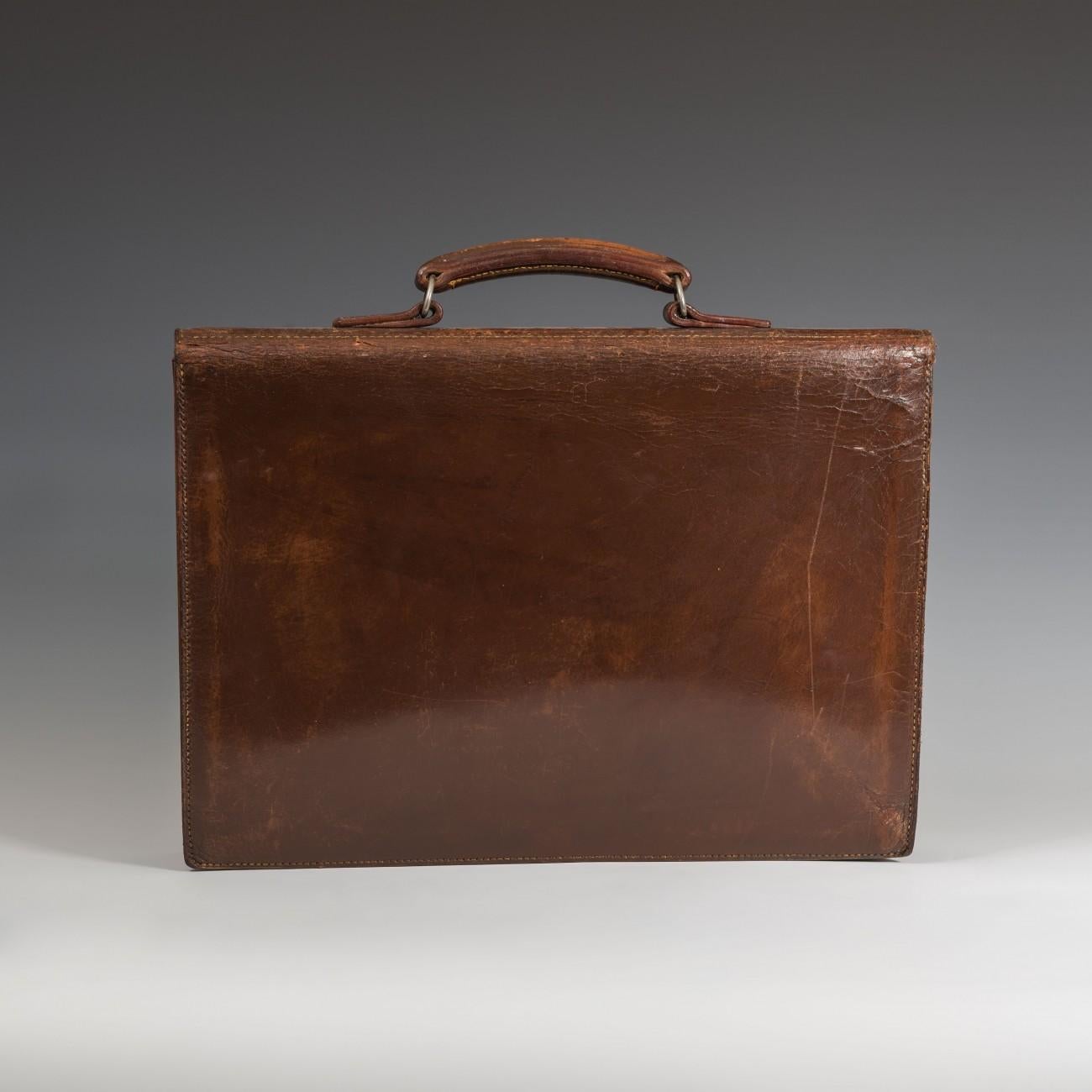 A handsome English made leather three pocket briefcase with two buckled straps and central chrome-plated adjustable catch, circa 1950.

Dimensions: 40.5 cm/16 inches (length) x 29 cm/11? inches (height) x 5.5 cm/2? inches (thick)

Bentleys are