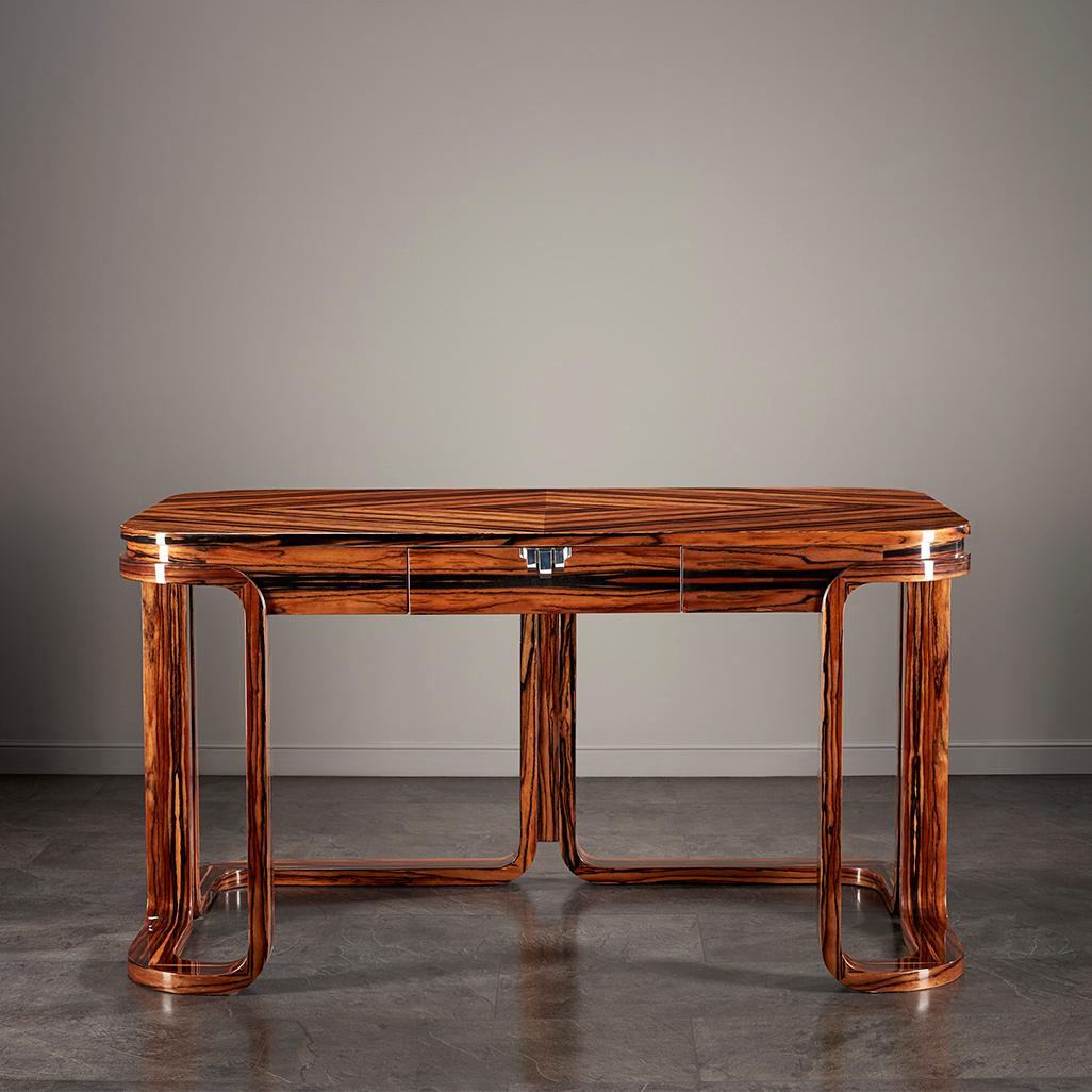 FLAPPER WRITING DESK

A truly nostalgic piece of art with a whiff of modernity. The playfully curved symmetric legs hold the thin shape together, topped with a wide desktop of admirable rounded edges. Its drawer with a jewel knob evokes a charming