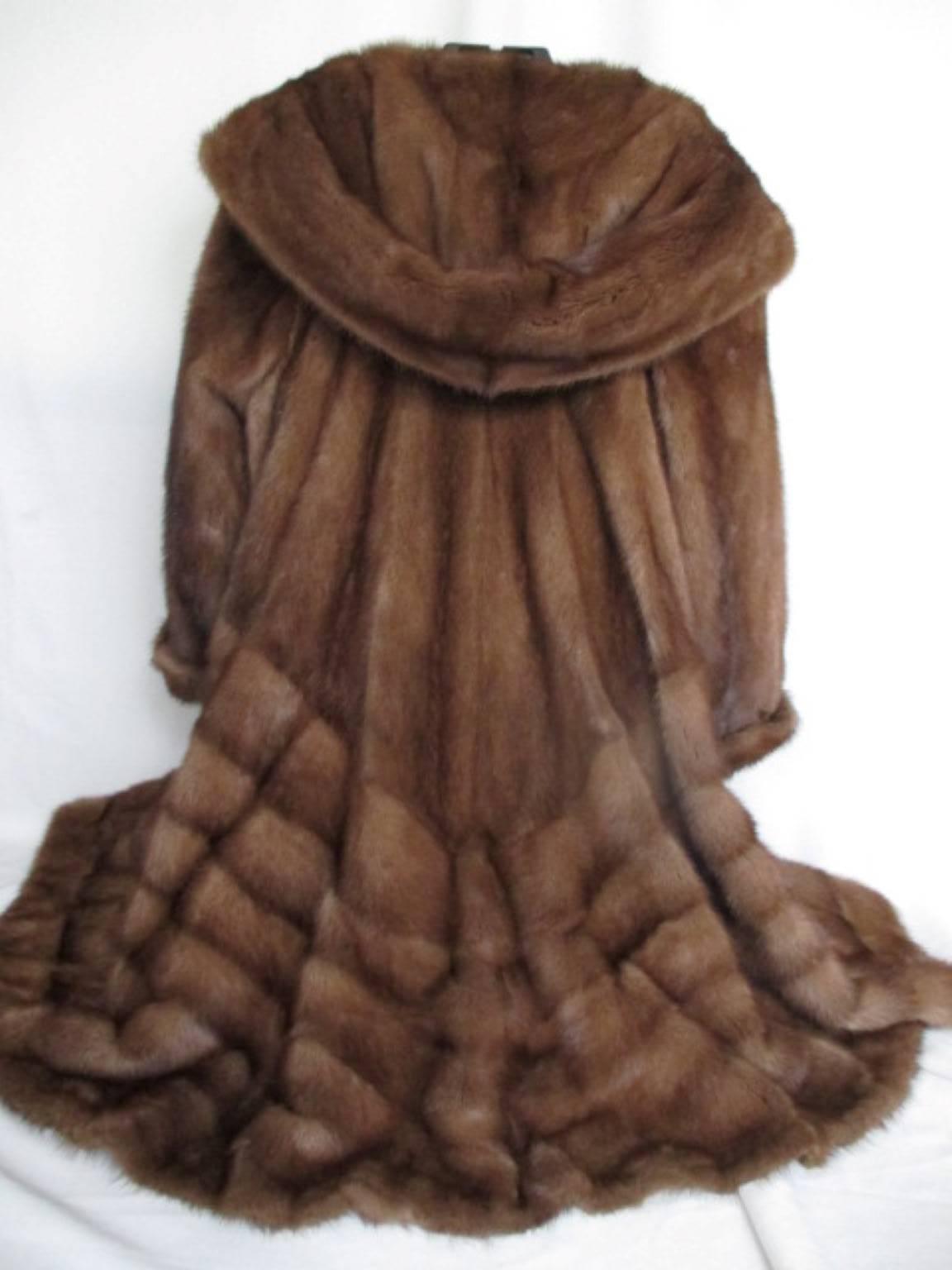 This flared 3/4 length chestnut brown mink coat is made of quality fur with a large hood, 2 buttons at the collar, 3 closing hooks and 2 velvet pockets.
It's in good vintage condition with some minimal wear at the cuffs.
These coats are rare to