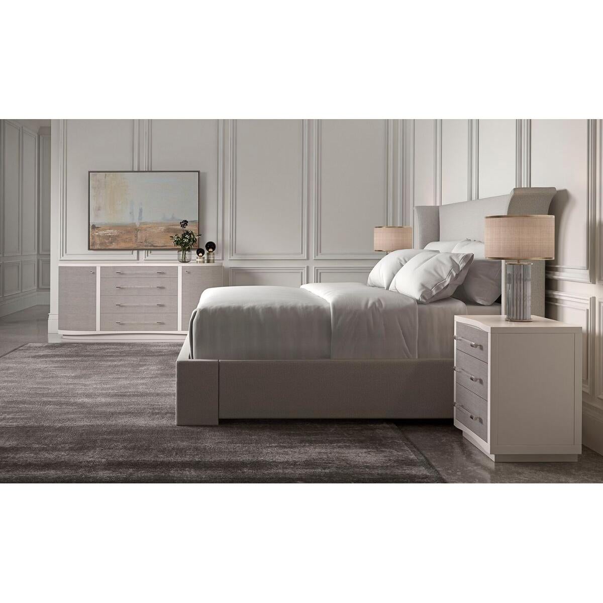 An elegant US king-sized upholstered bed frame featuring a high headboard that is flared out and curves gently at the sides. The frame is wrapped in a light natural color fabric with a subtle textured finish, which suggests a contemporary design