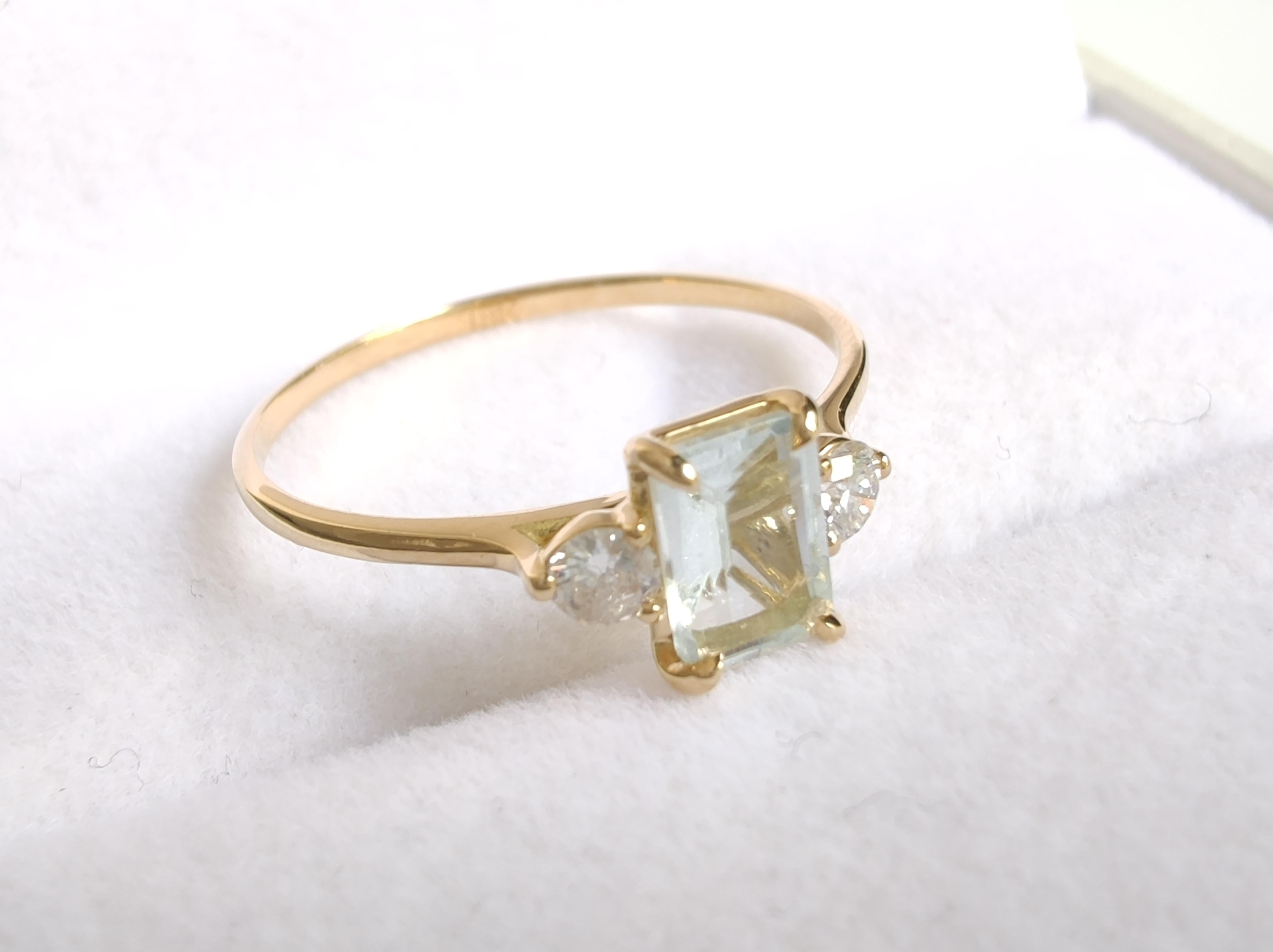 Embrace elegance with our classic 18K gold ring, featuring a central emerald-cut aquamarine flanked by brilliant diamonds. Perfect for daily wear or as a unique engagement ring, this timeless piece adds a touch of sophistication to any outfit.