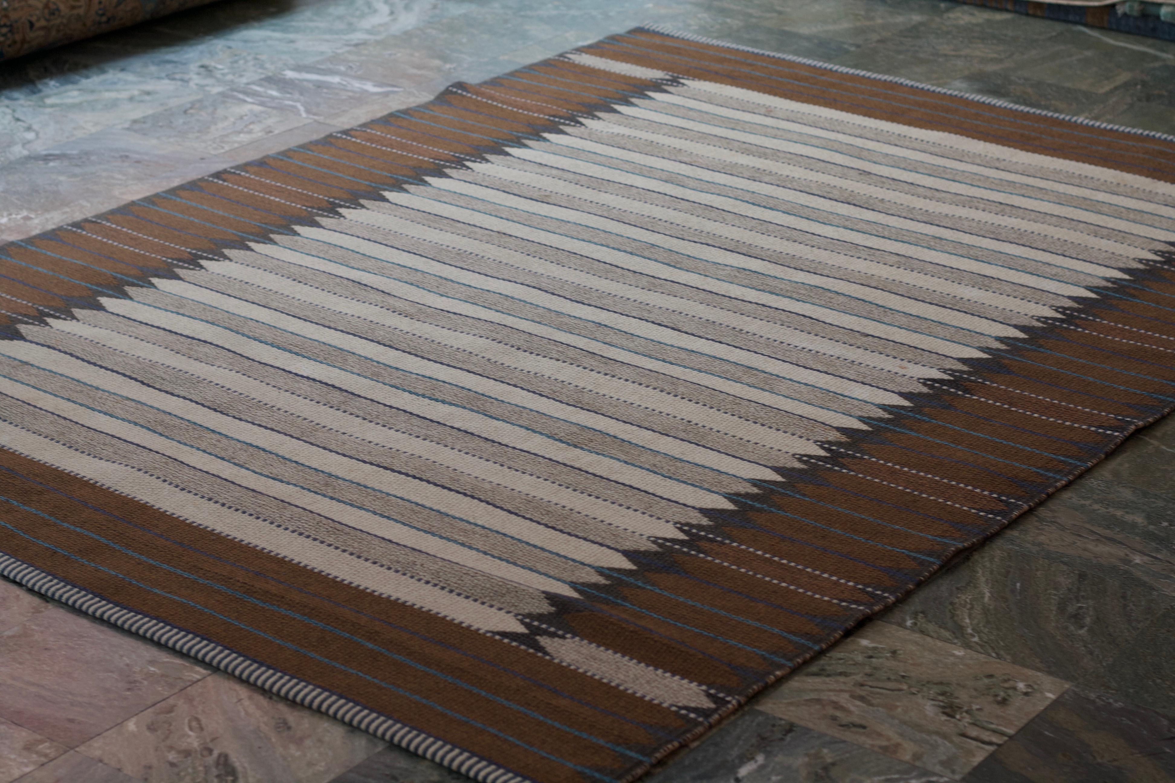 A beautiful flat weaved double sided rug created by textile designer Ingrid Dessau in Sweden ca 1950. Brown and white on one side and two shades of brown on the other side, both sides with details in blue. The rug is handwoven in wool. Sold in