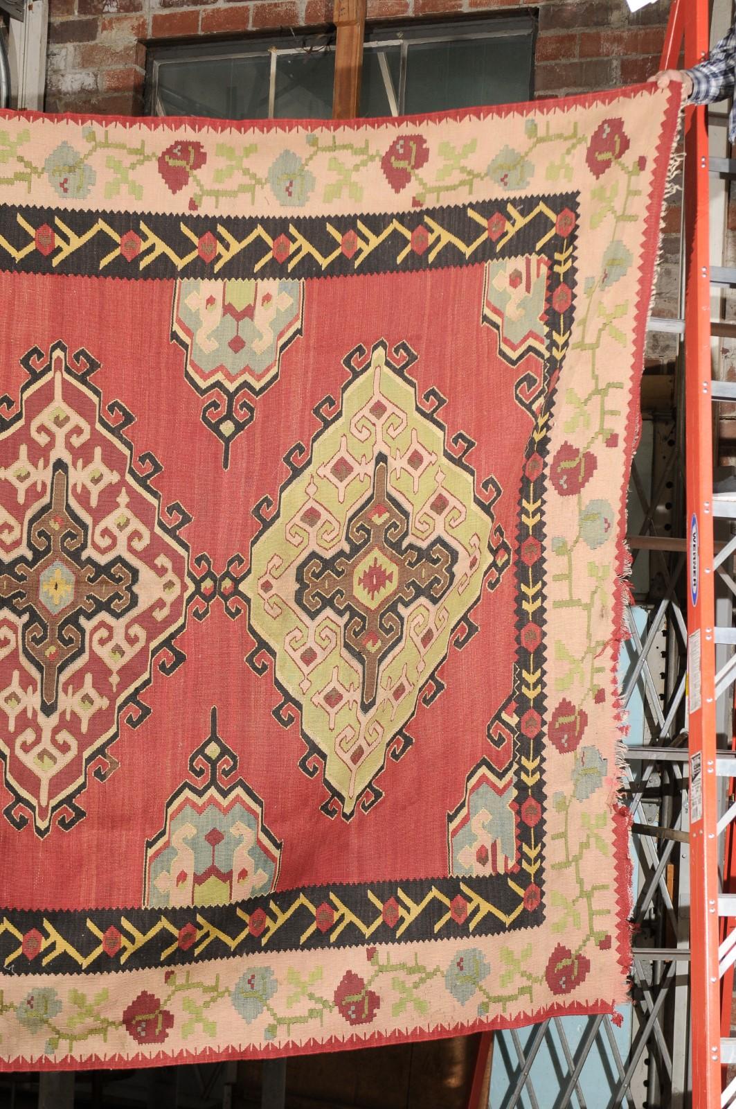 Flatweave Area Rug in Reds, Tans, & Black featuring Floral Border In Fair Condition For Sale In Atlanta, GA