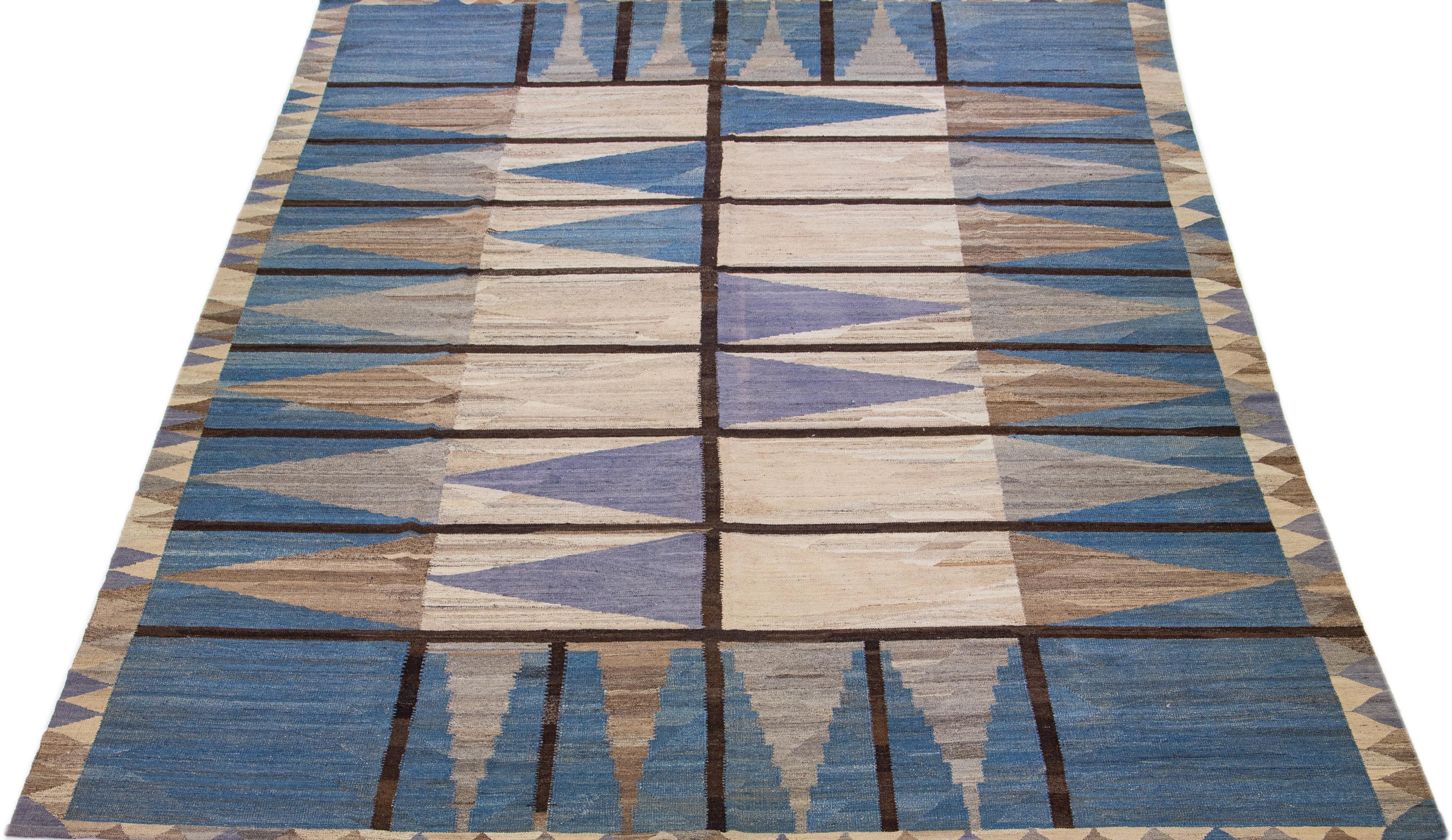This flatweave wool rug exhibits a captivating brown field with blue accents, creating a contemporary and aesthetically-pleasing effect. This fashionable design is crafted with a special wool blend, ensuring superior durability and resilient
