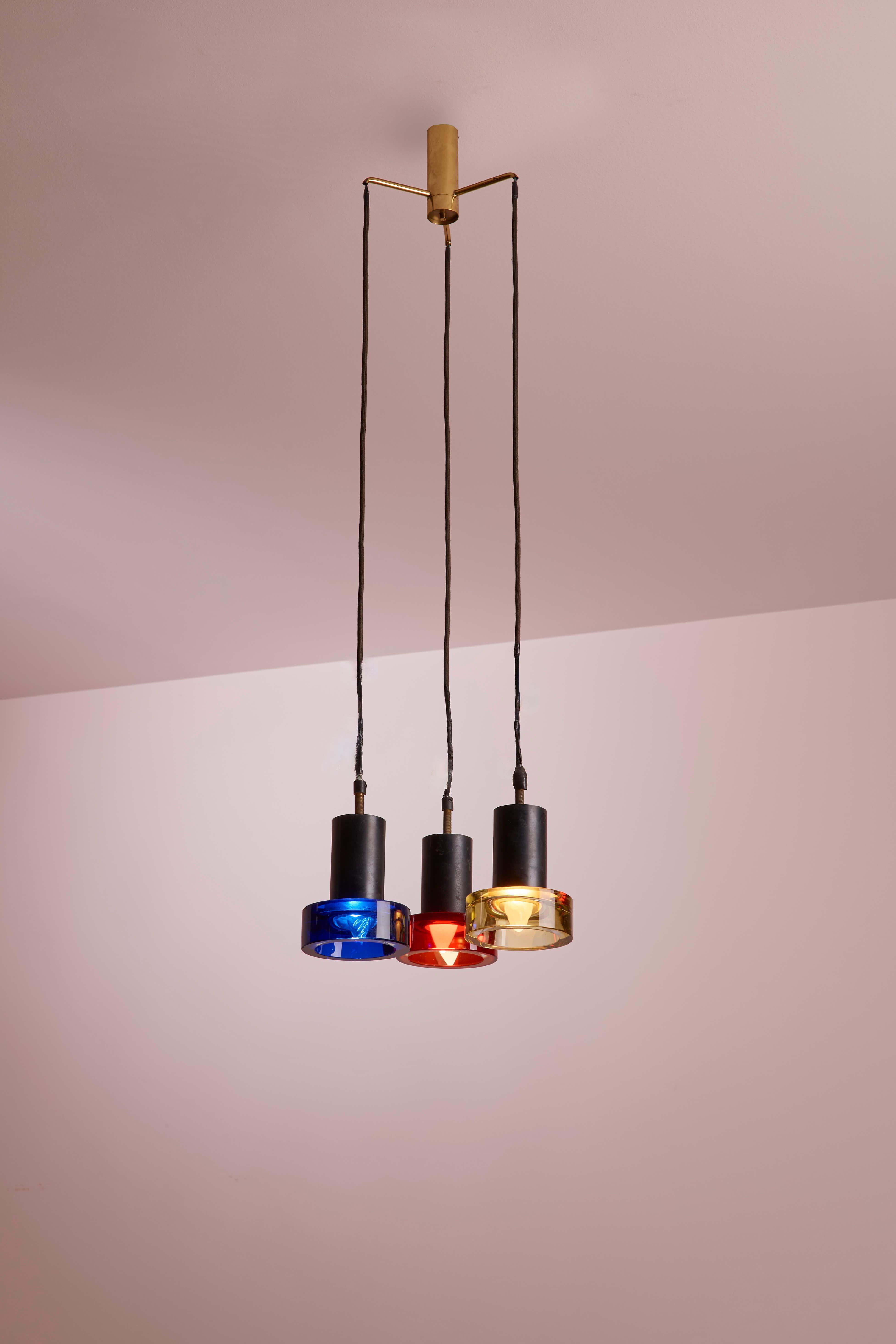 Lampada a sospensione colorata in ottone naturale e metallo verniciato con tre paralumi in vetro di diversi colori, disegnata da Flavio Poli per Seguso, anni '60.

Scendendo delicatamente dal soffitto, questi tre paralumi in vetro colorato rivelano