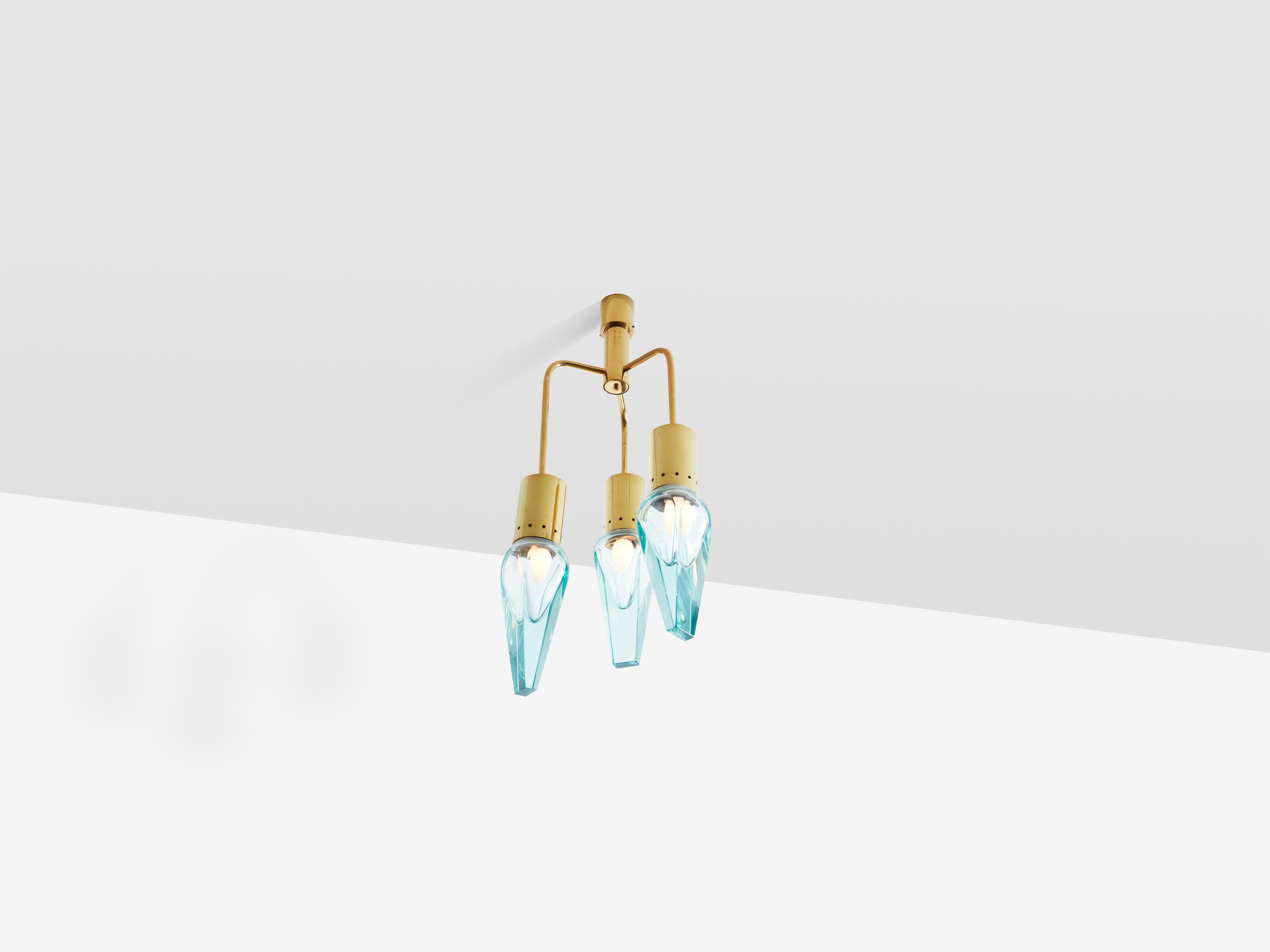 This Murano glass and brass chandelier was designed by Flavio Poli for Seguso in the 1950s. Featuring three conical luminaires, it beautifully showcases the Sommerso glass technique, where layers of different materials overlap, creating a variety of