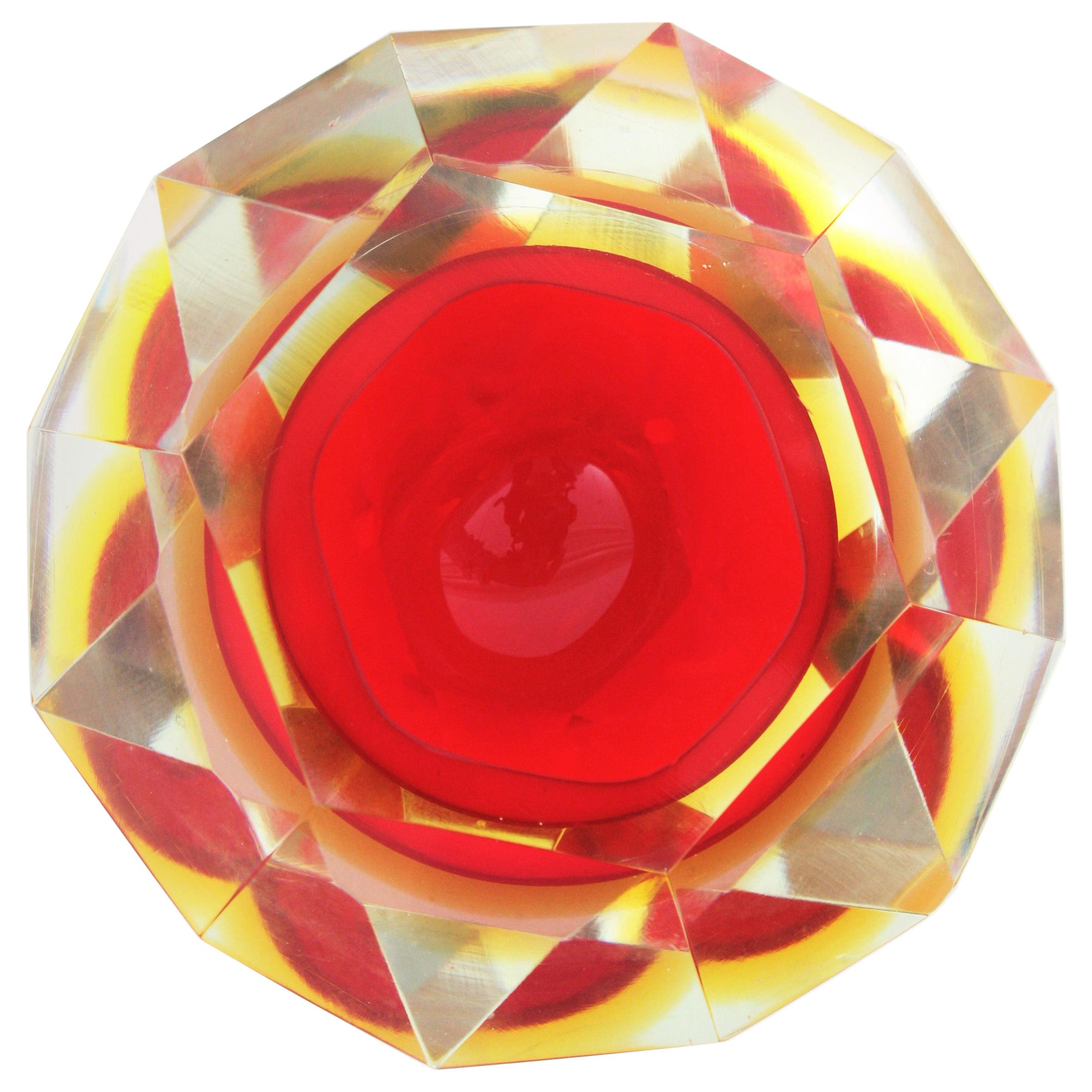 Flavio Poli Sommerso red and yellow diamond shaped faceted Murano glass bowl. Attributed to Flavio Poli for Seguso, Italy, 1950s.
This Midcentury Modern vibrant red Murano glass bowl has a layer in yellow glass submerged into clear glass using the