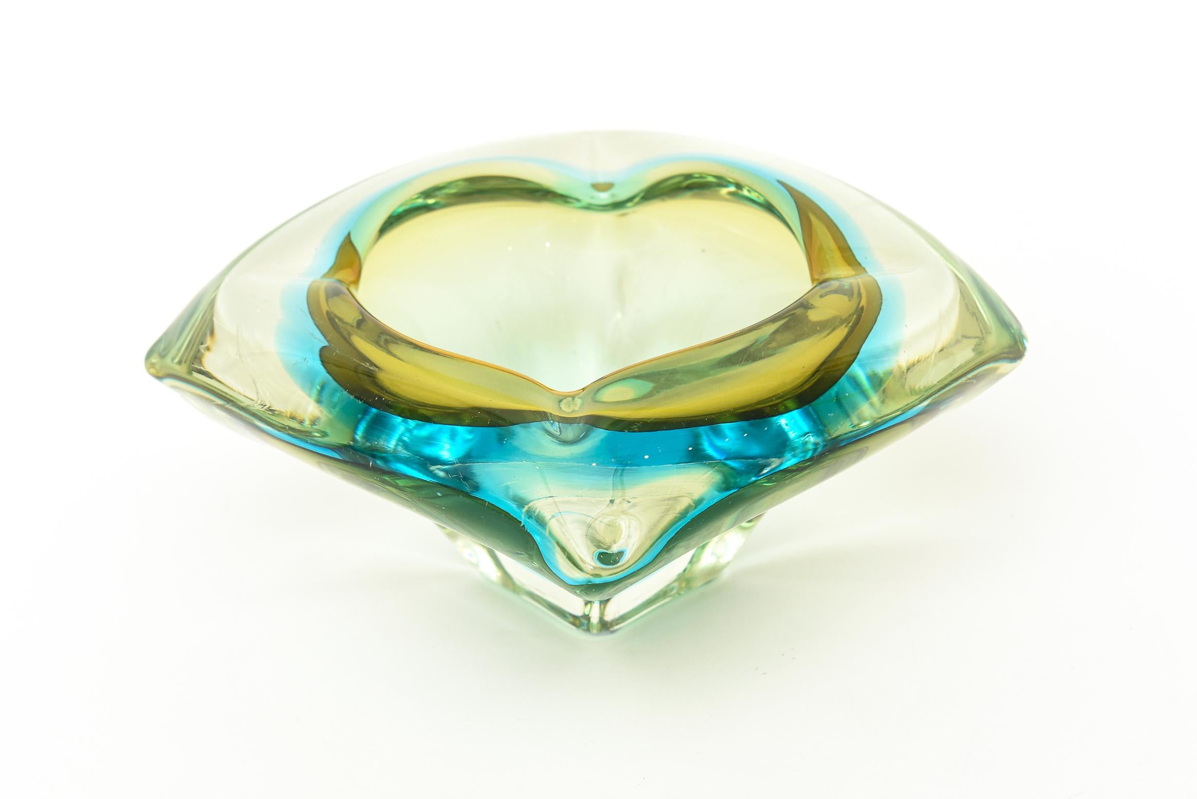 This large chunky vintage Italian Murano glass bowl by Flavio Poli is layers of luscious sommerso glass of turquoise and shades of greens with a hint of amber depending on the play of light. It has 4 very small indentations on all the sides. Perhaps