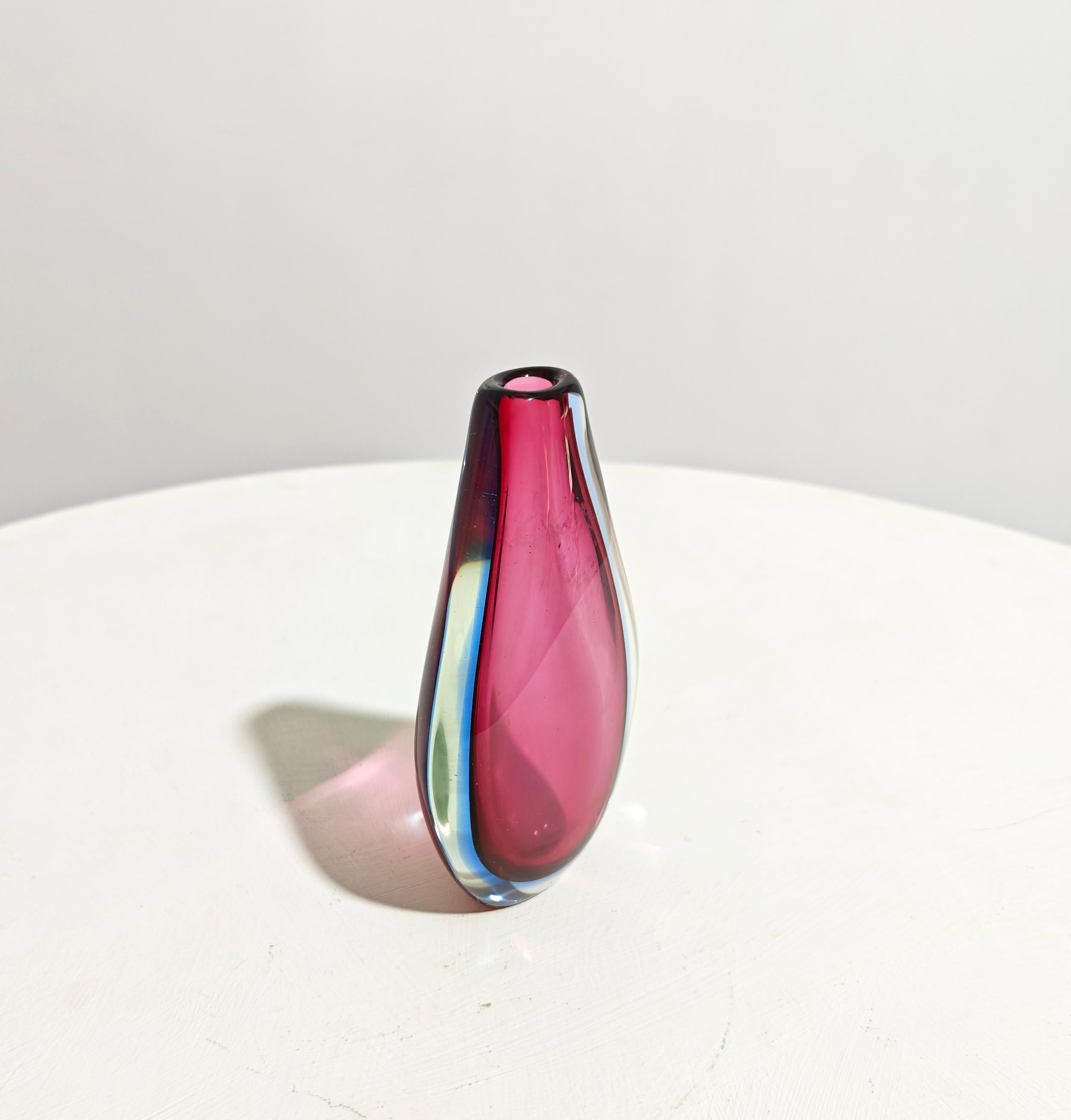 FLAVIO POLI. Producción Seguso Vetri d'Arte, Diseño Italia 1950 ca.
Jarrón de vidrio sommerso incoloro, azul claro y lila, cuerpo en forma de gota con boca circular plana. Por favor, mira atentamente el vídeo y las fotos, gracias.

Peso: 1.500