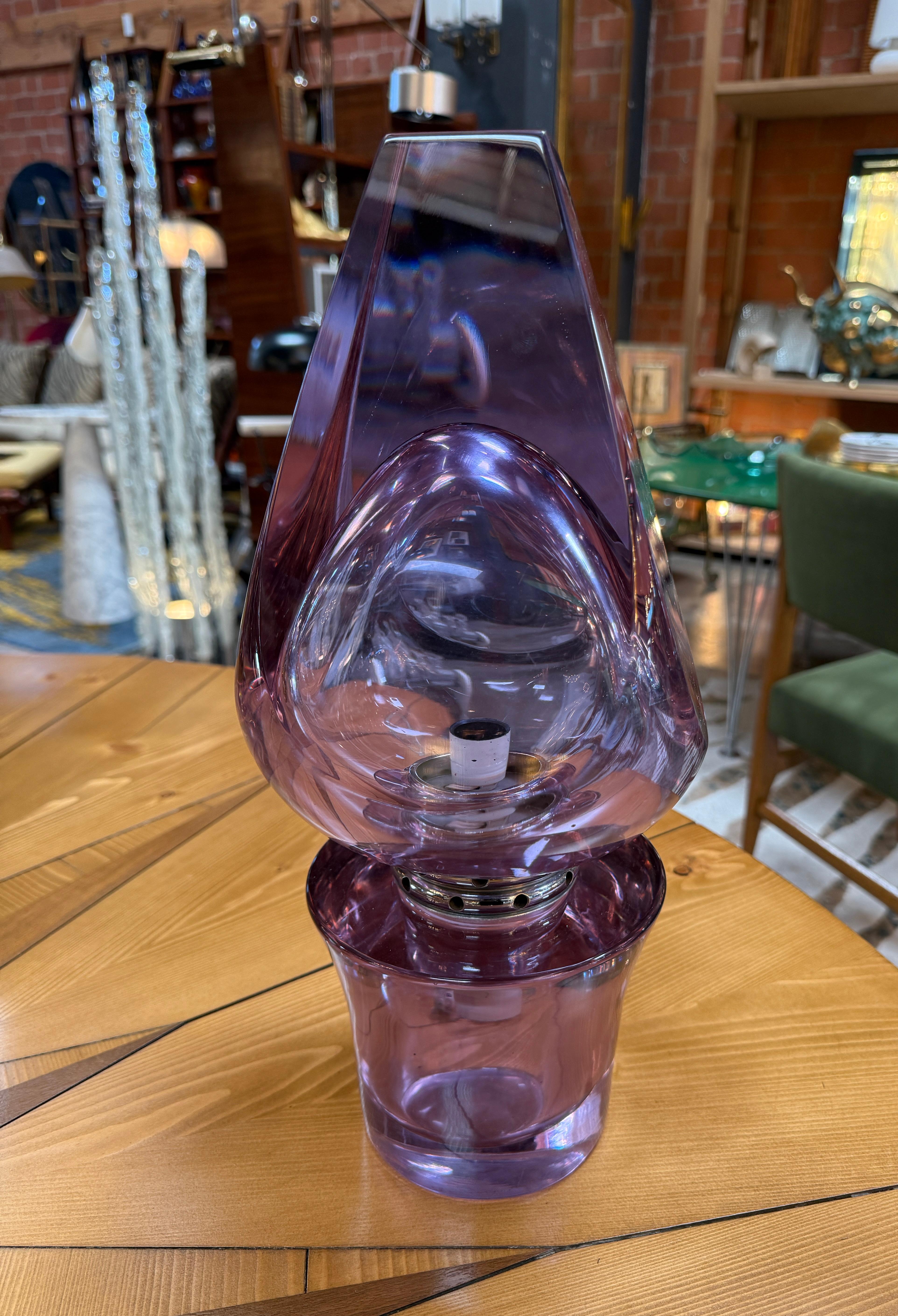 A Flavio Poli Seguso sculptural murano glass table lamp crafted in Italy during the 1970s. This striking piece features a bold teardrop silhouette in vivid amethyst glass, masterfully hand-blown with thick, organic contours that catch and refract
