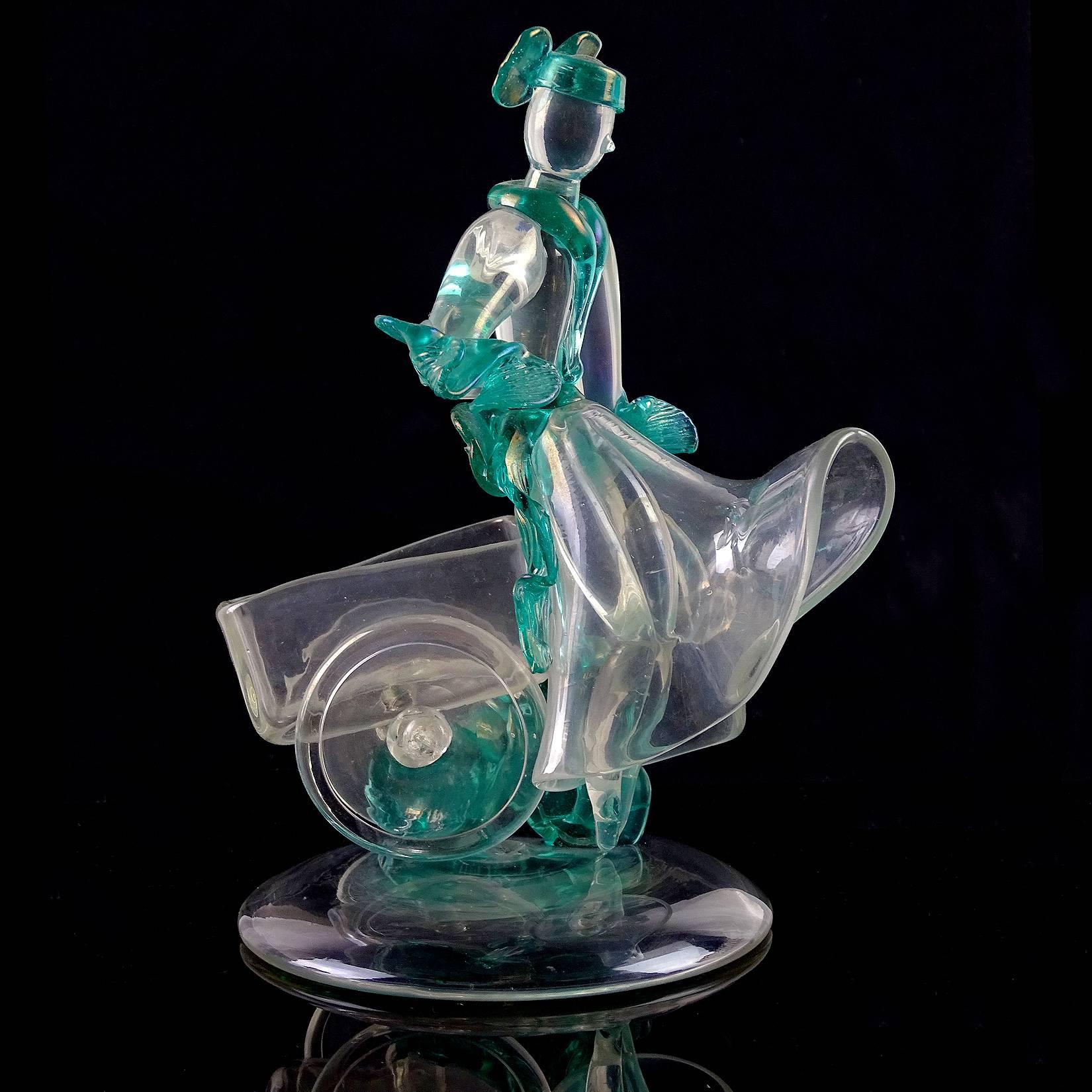 Rare and beautiful antique Murano hand blown iridescent Italian art glass woman figurine / sculpture, sitting on a cart. Documented to designer Flavio Poli for Seguso Vetri d'Arte, circa 1930s. Her costume has green accents throughout. Nicely