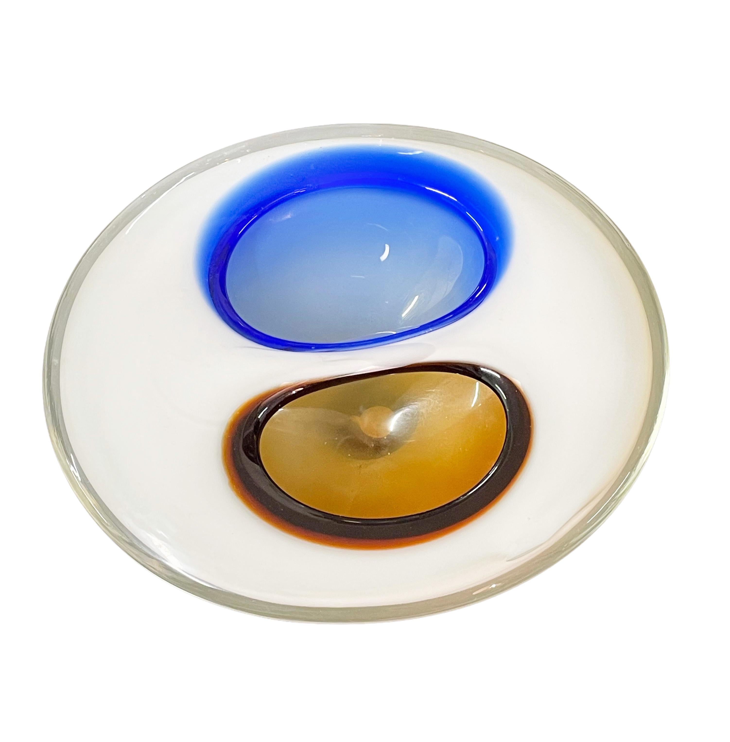 Unglaubliche Mitte des Jahrhunderts Murano Kunstglas weiß mit zwei Taschen in blau und dunkel bernsteinfarben. Dieses fantastische Stück wurde in den 1970er Jahren in Italien entworfen und wird Flavio Poli zugeschrieben.

Die Linienführung ist
