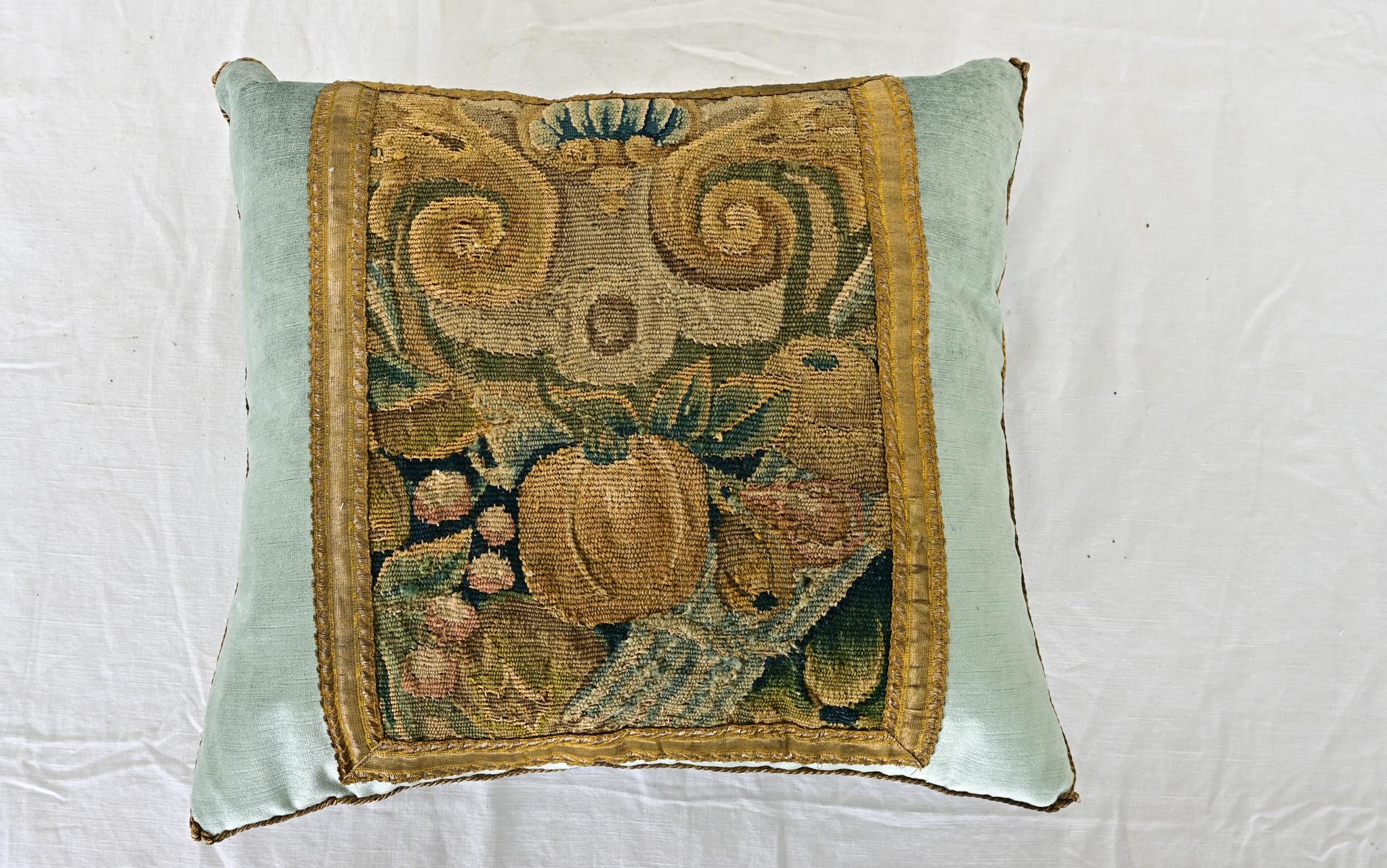 A recently made pillow featuring a 17th century Flemish tapestry fragment in shades of soft blues, greens, browns and taupe. Framed with antique gold galloon metallic tape trim on pale blue cape velvet, complementing the vegetal and foliate themes.