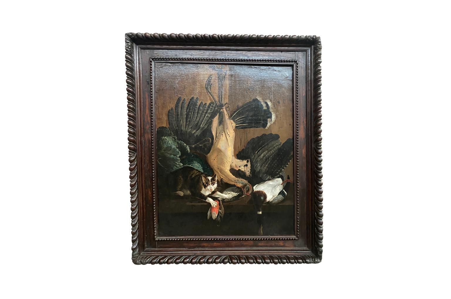 Un olio su tela Nature Morte - Natura morta della metà del XVIII secolo, molto accattivante, racchiuso in una bella cornice.  Un affascinante gatto protegge il pollame.  Sullo sfondo, nota le meravigliose pareti in legno.