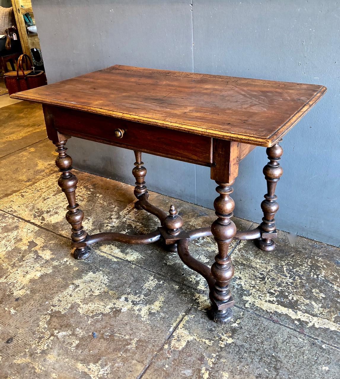 This is a good example of a Late Baroque Flemish (Netherlands) side or writing table, circa 1700. The table is crafted of solid walnut, features beautifully turned legs, serpentine stretcher, and center finial. There are some restorations to the