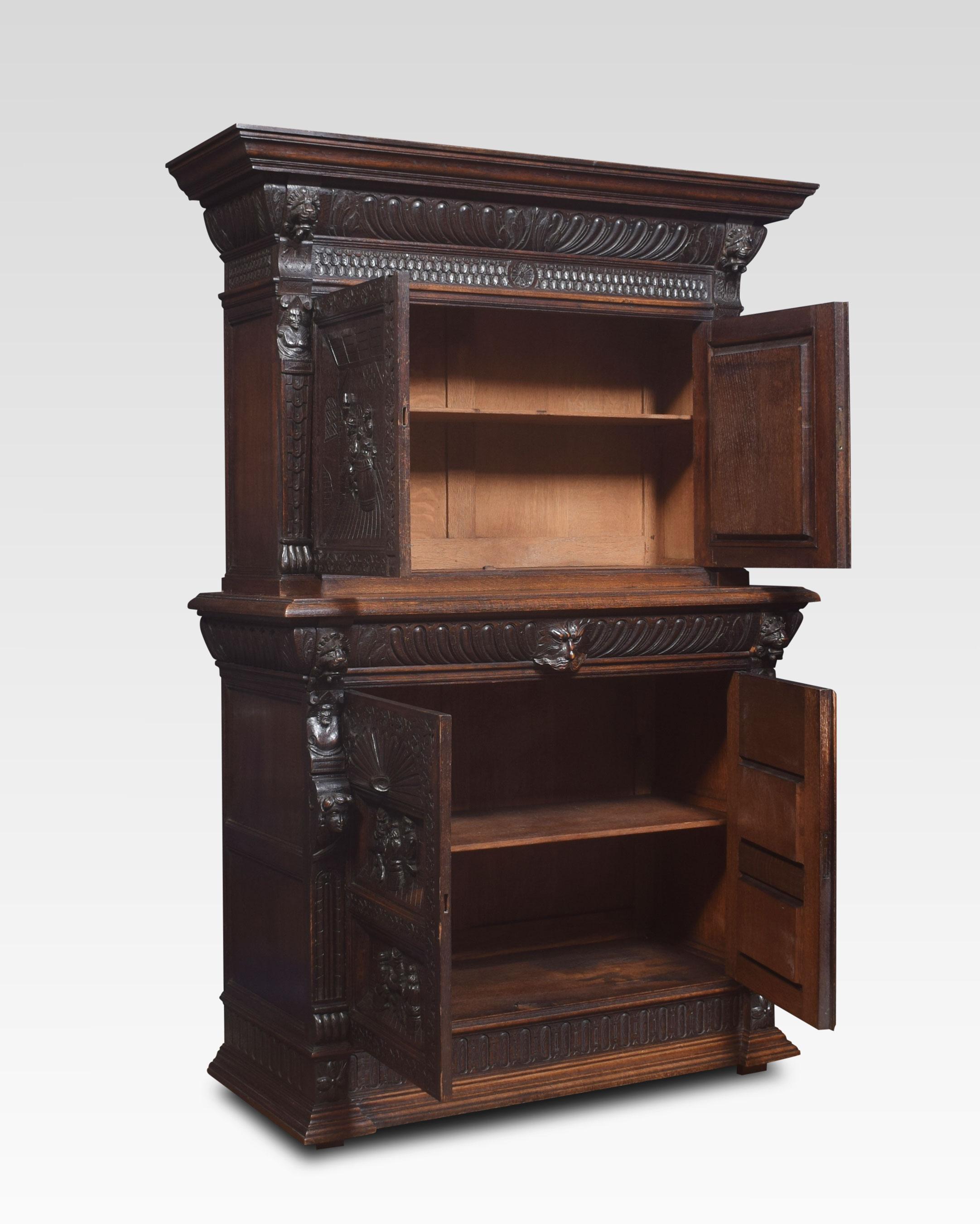 Flemish carved oak cupboard, the projecting corning over two carved panel doors depicting tavern scenes opening to reveal an adjustable shelved interior. The base section fitted with a drawer with a green man mask and carving above a further pair of