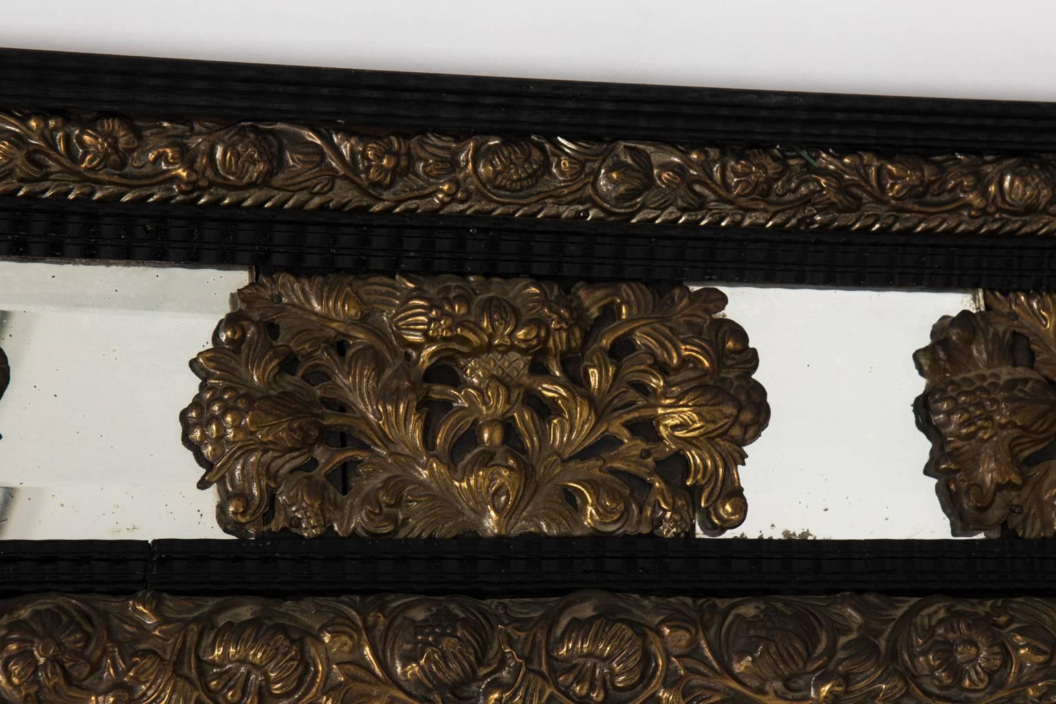 Repousse mirror with pinecone decoration in gold gilt with black lacquered trim, circa early 20th century.
   