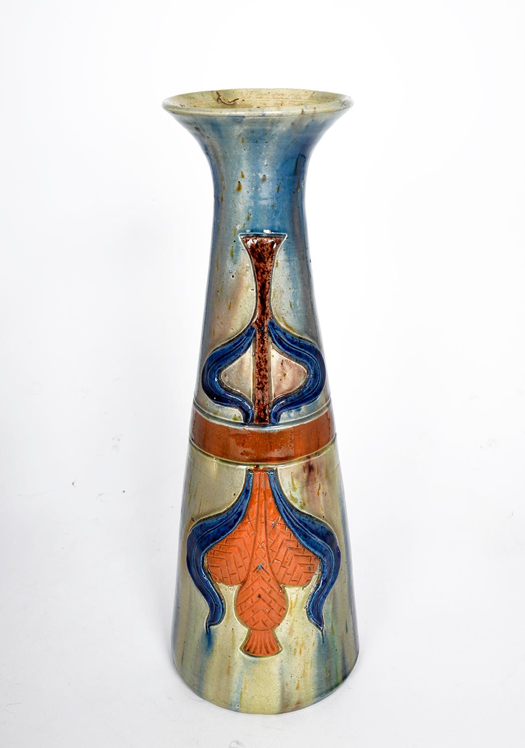 This tall and very stylish conical Art Nouveau vase is a beautiful example of Flemish pottery or ‘Poterie Flamande’ from Torhout dating from the 1900s. The vase is a rainbow of colours created by a drip glaze of brown, blue, yellow and orange. It