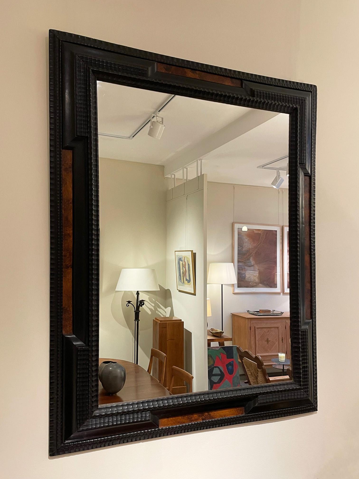 A Flemish style carved and ebonized beech ripple frame mirror, with faux burr walnut ornaments.
Continental, first half of the 20th century.