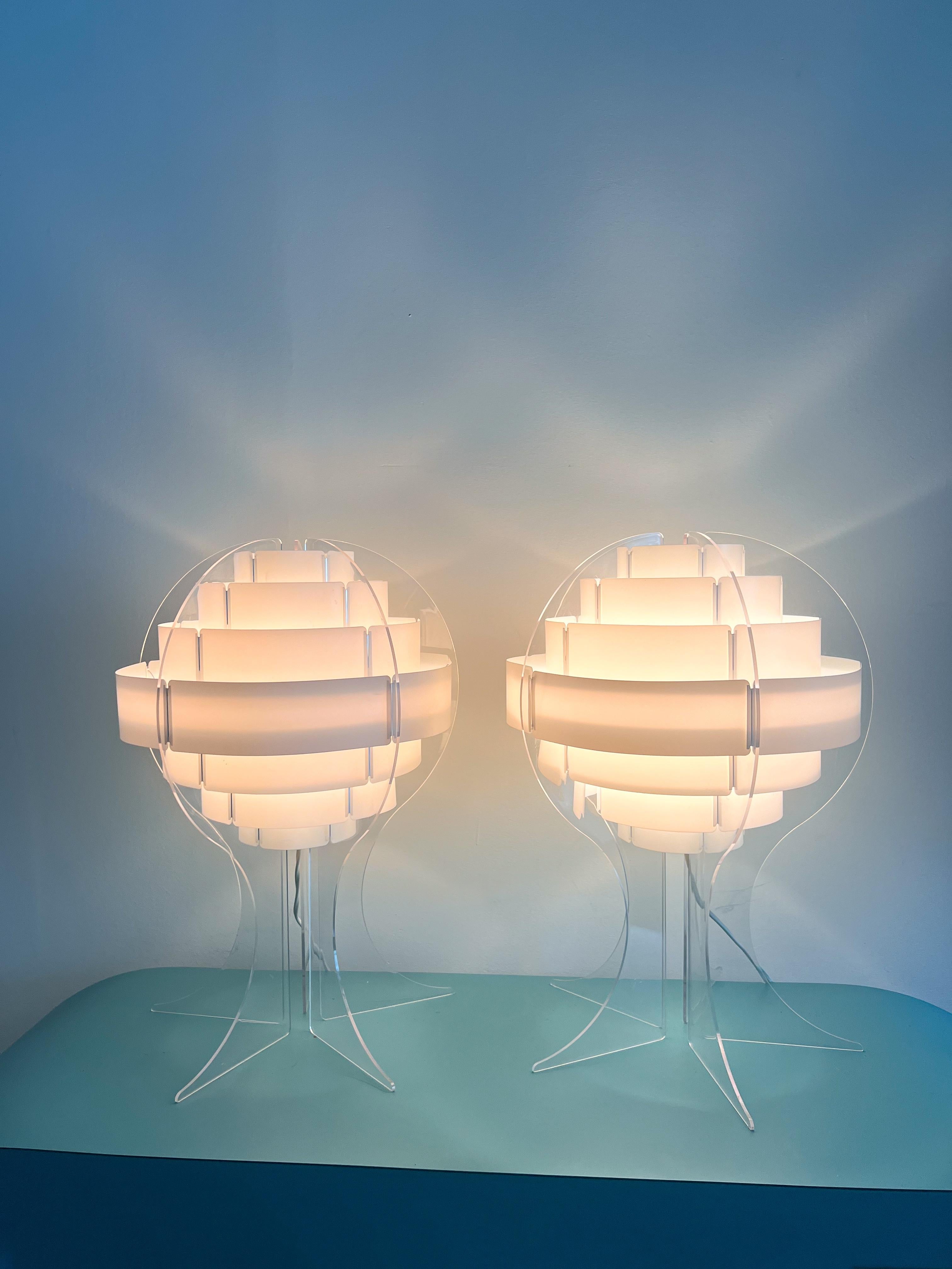 The 'Strips' table lamp, crafted in the late 1960s to early 1970s by Preben Jacobsen & Flemming Brylle in Denmark, showcases a stylish and unique design. Featuring a transparent acrylic base that cradles a shade composed of interconnected white