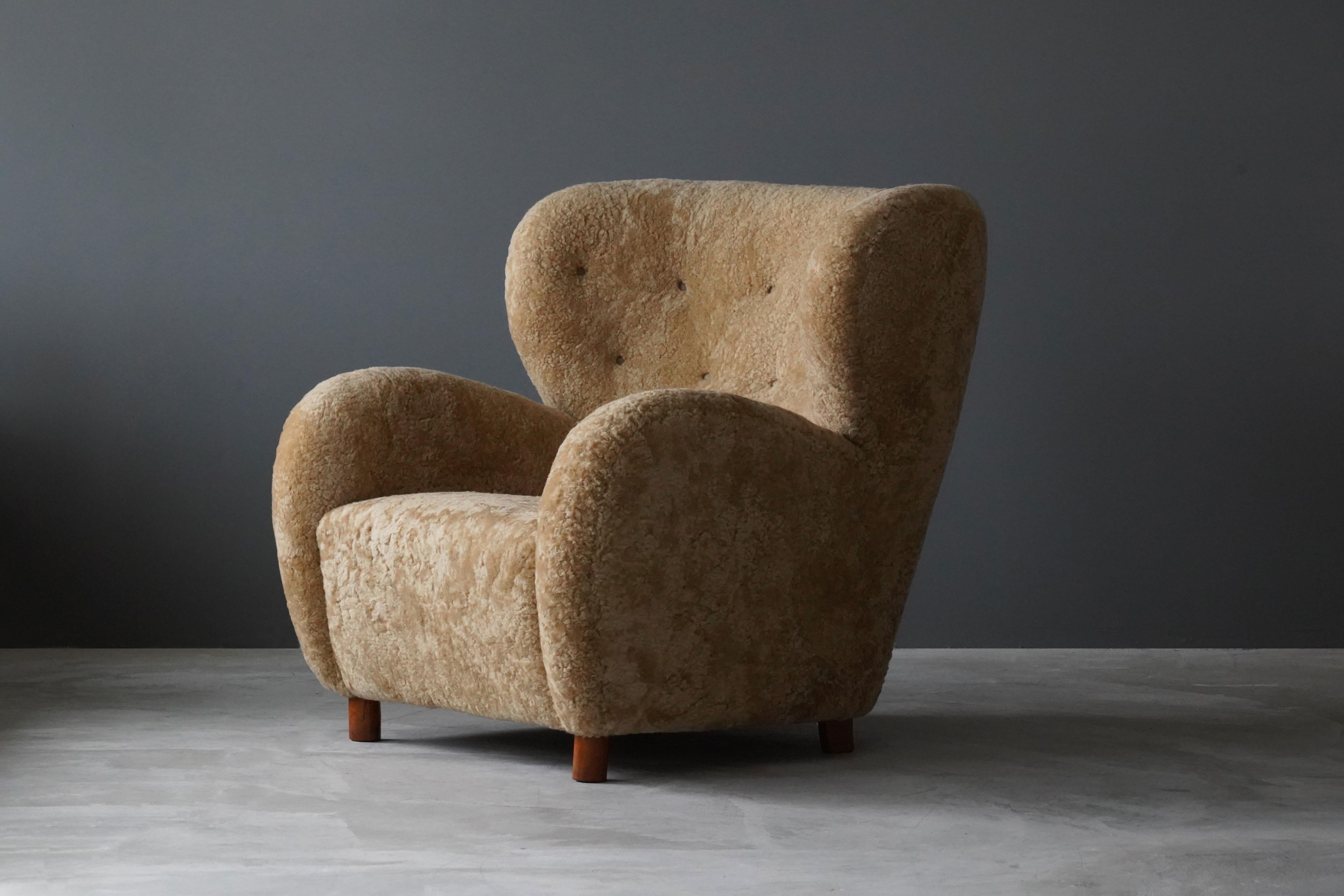 A rare organic lounge chair. Design attributed to Flemming Lassen. Presumably manufactured by A.J. Iversen. The chairs organic form is further enhanced by sheepskin upholstery. Features highly modernist beech legs. 

