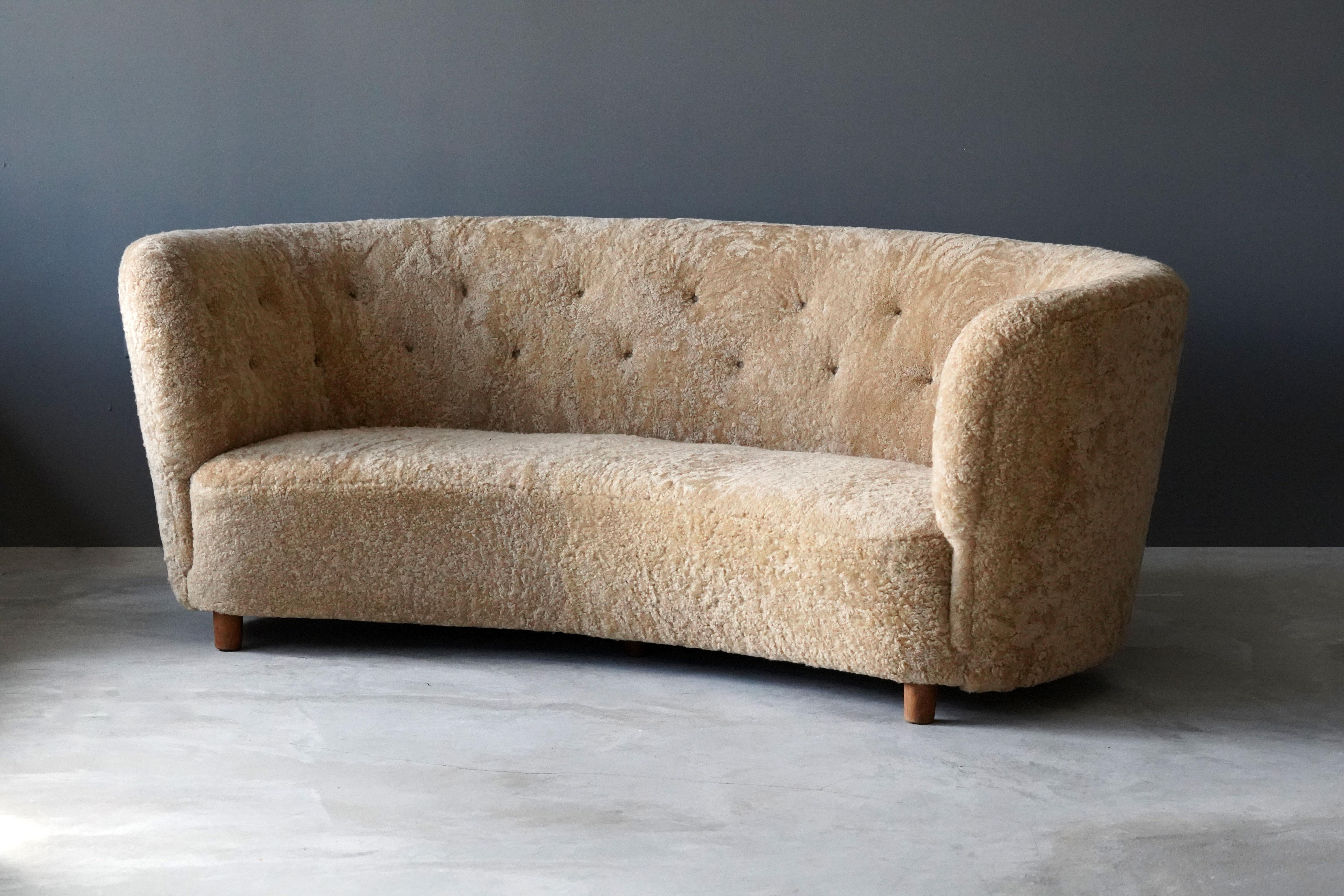 An organic sofa. Produced in Denmark, 1940s. Design attributed to Flemming Lassen. Reupholstered in brand new sheepskin upholstery. 

Compare form to the 